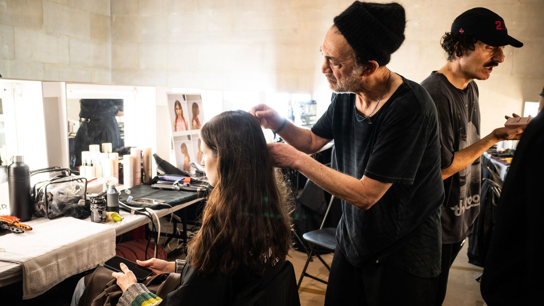 Celebrity hair stylist Eugene Souleiman preparing a model's hair backstage at Erdem