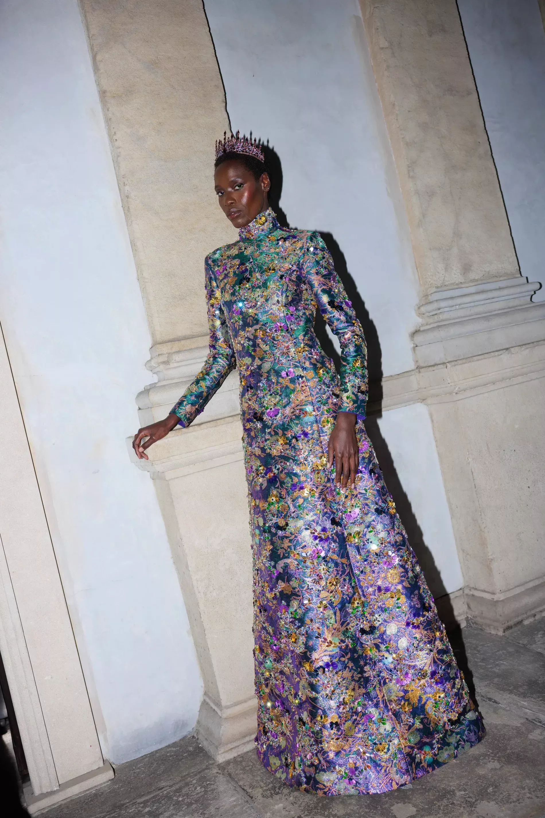 Awar Odhiang in Milan fashion week 2026 wearing the selected region shows a model wearing an ornate, shimmering multicolored floral-patterned high-neck gown from Gucci's Fall/Winter 2026/2027 collection by Demna