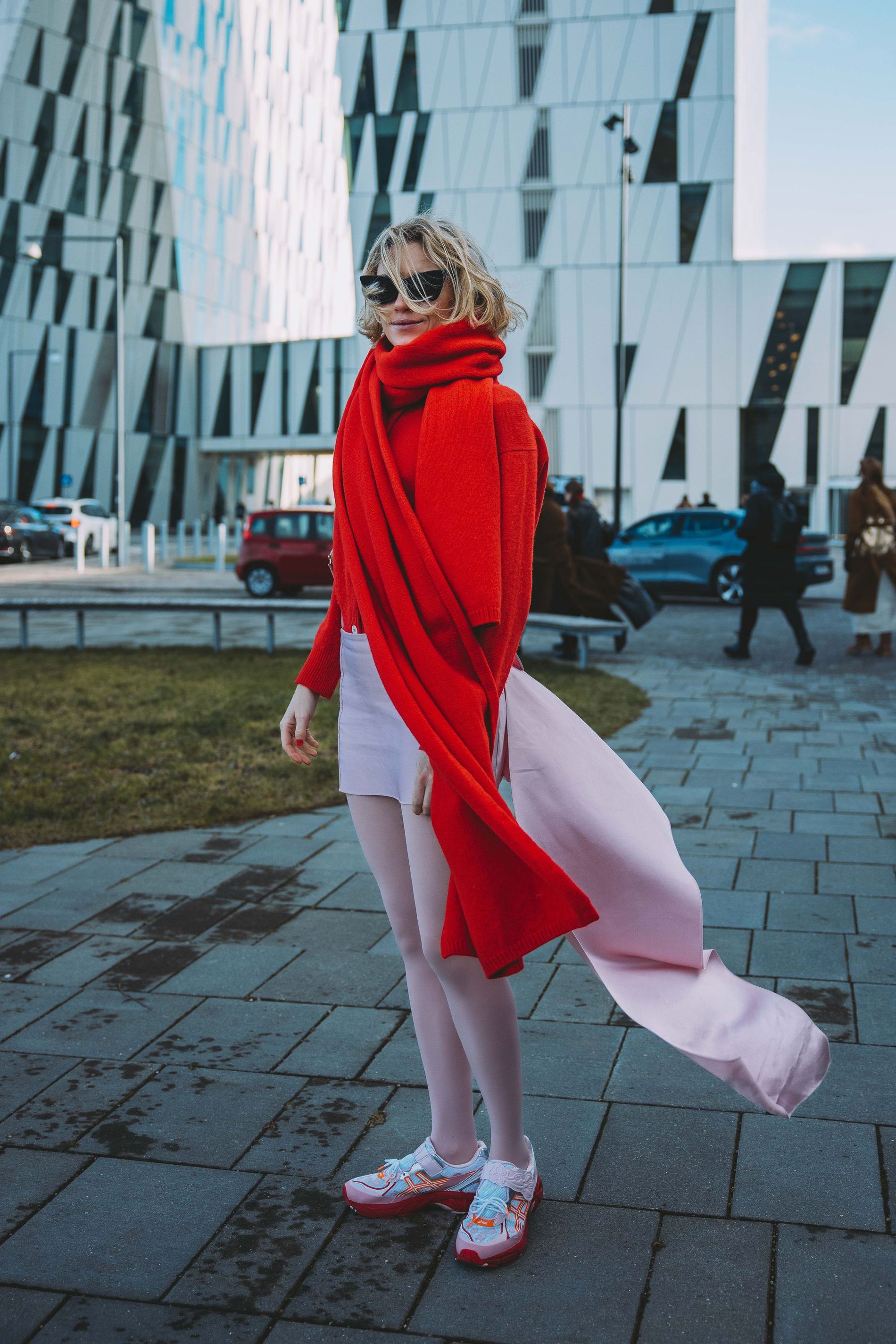 A guest wears the two-tone styling trend, pairing powder pink stockings and a skirt with bright red knitwear
