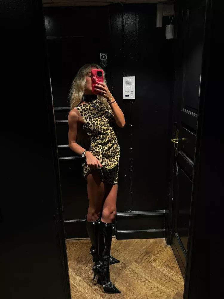 Emili Sindlev wears a leopard print mini dress with knee high boots