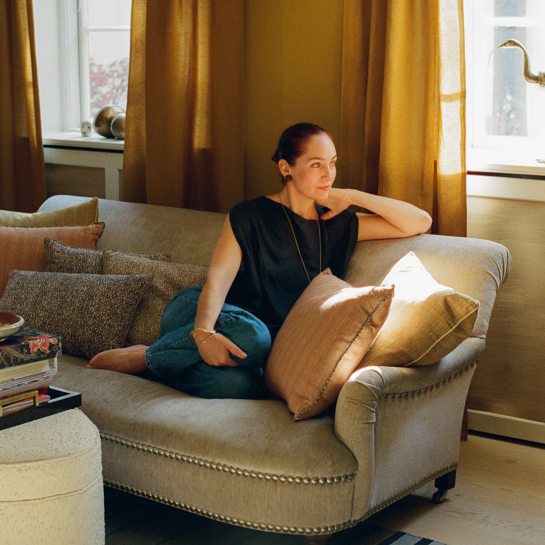 Helene Blanche sitting on a sofa, with light falling in form the window, surrounded by her pillows in the latest design, Leonard