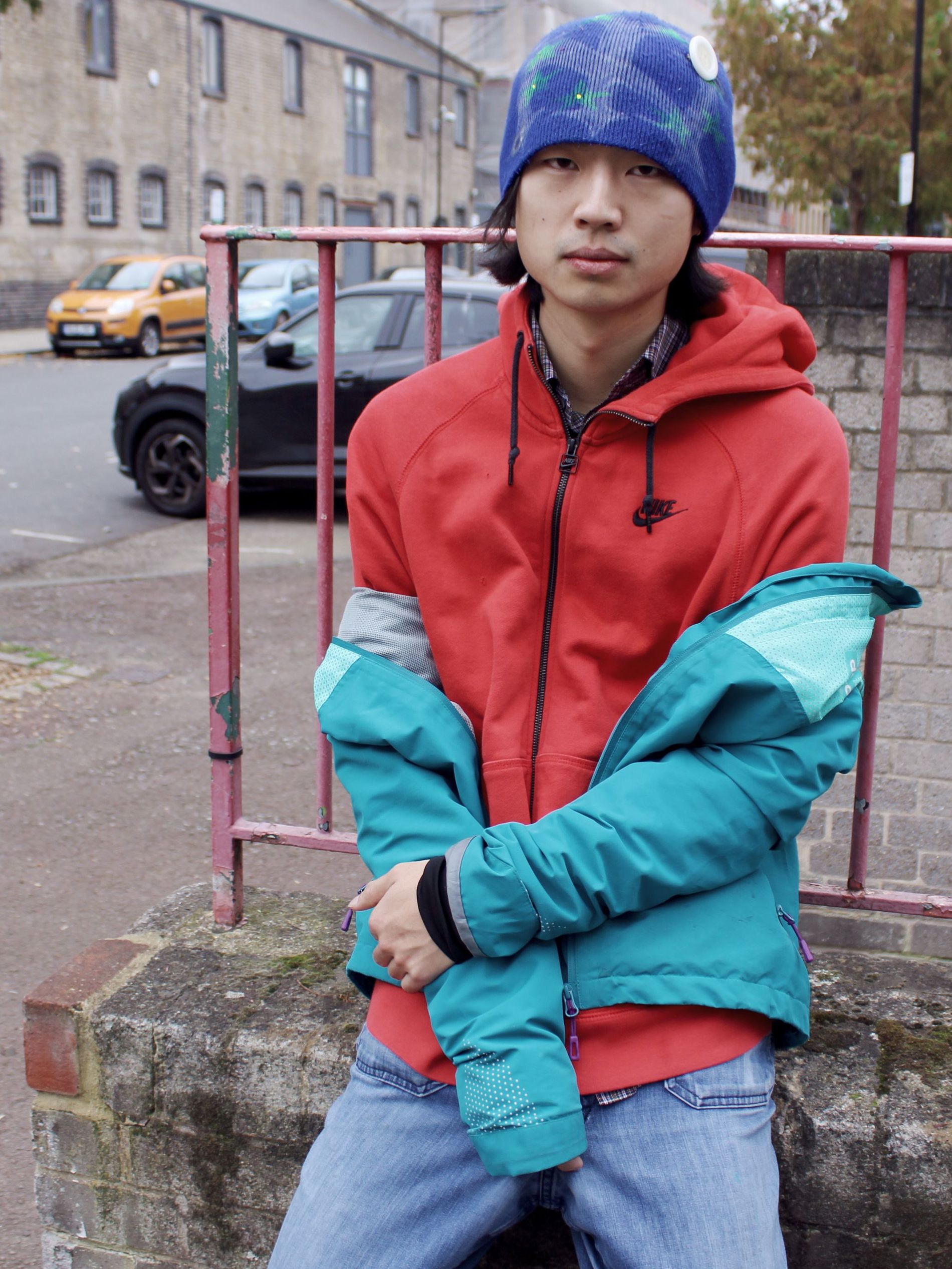 A man leaning on a fence on a street