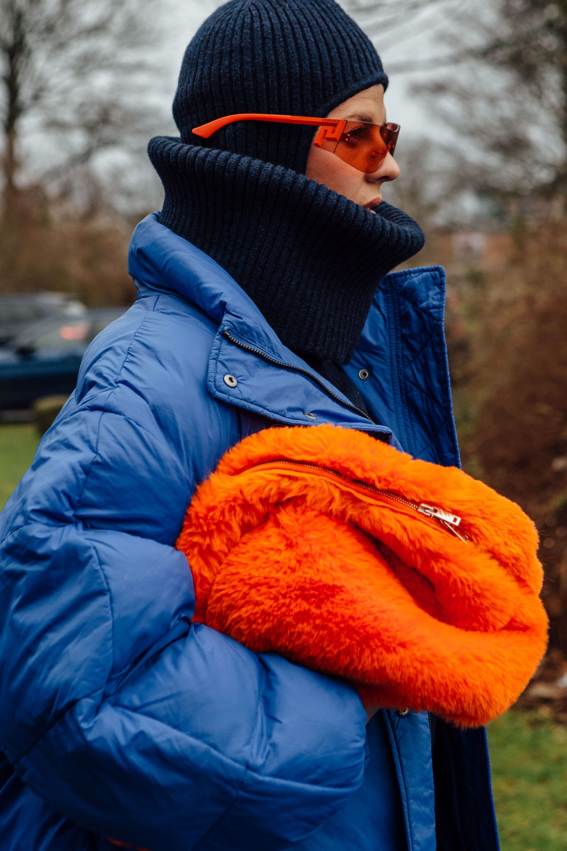 A guest wears an orange faux fur bag with matching glasses and a navy knit