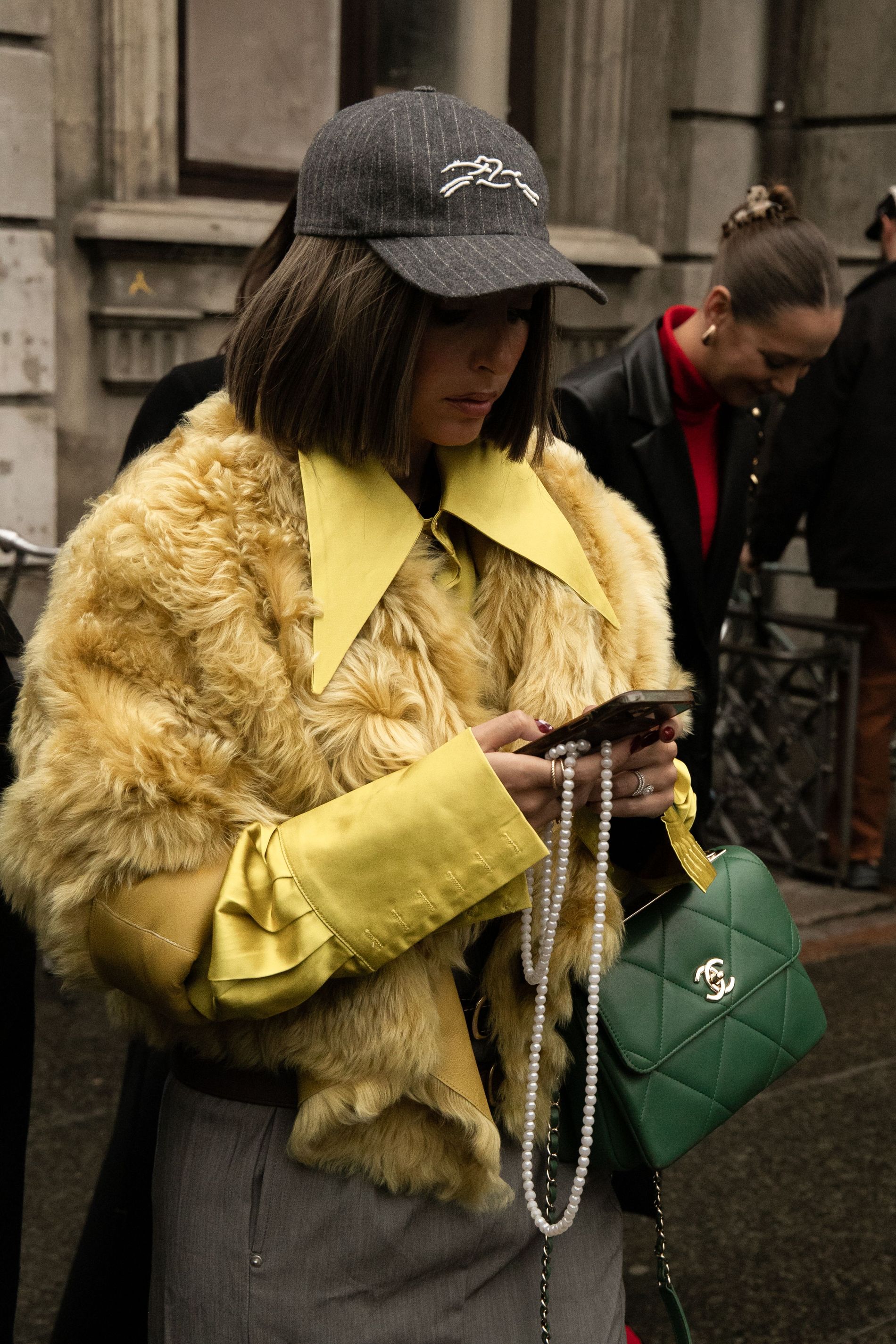 A guest at CPHFW wears a fellow silk shirt with a yellow faux fur jacket while posing for street style