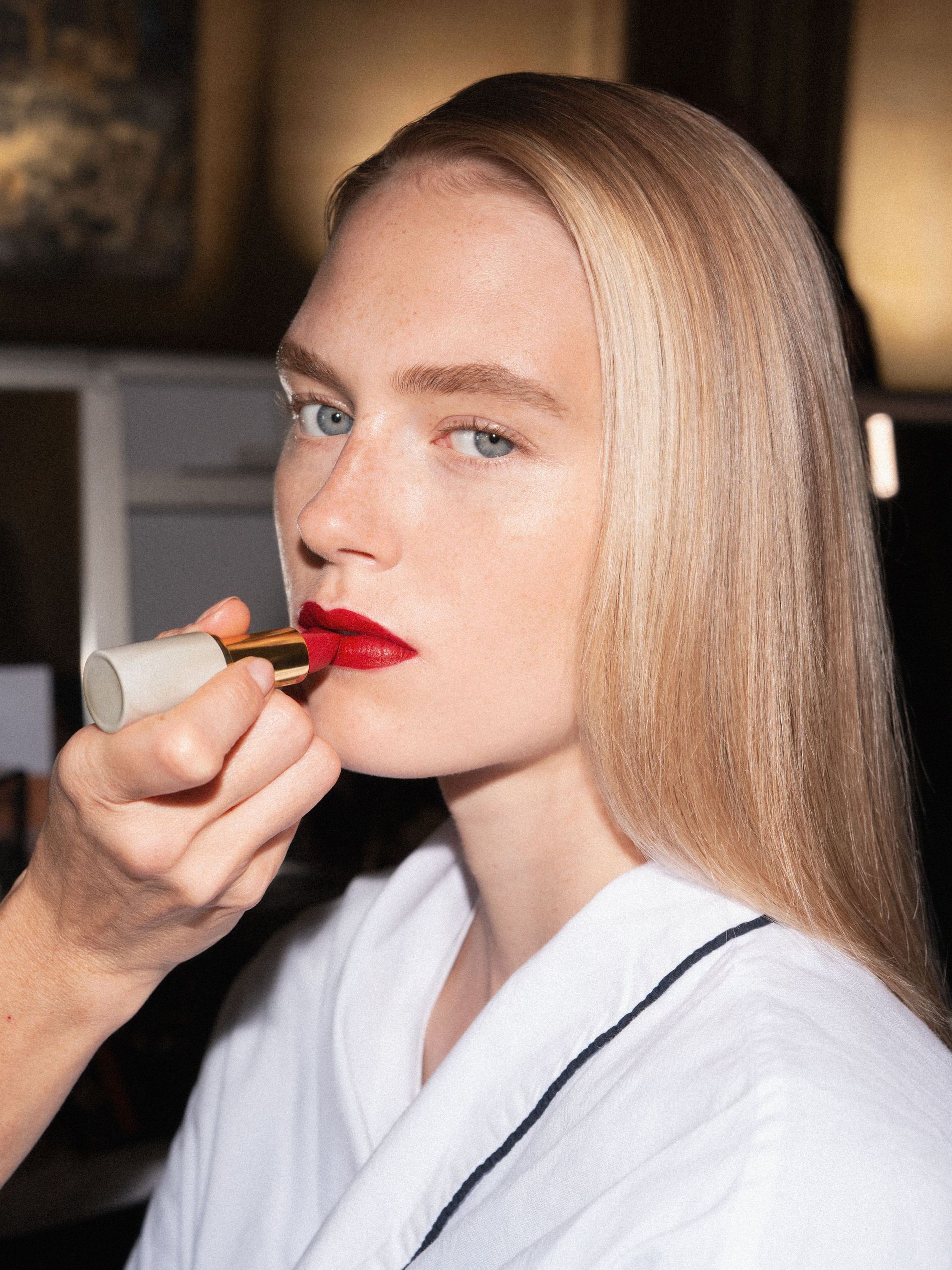 A model backstage at Victoria Beckham SS27 has red lipstick applied