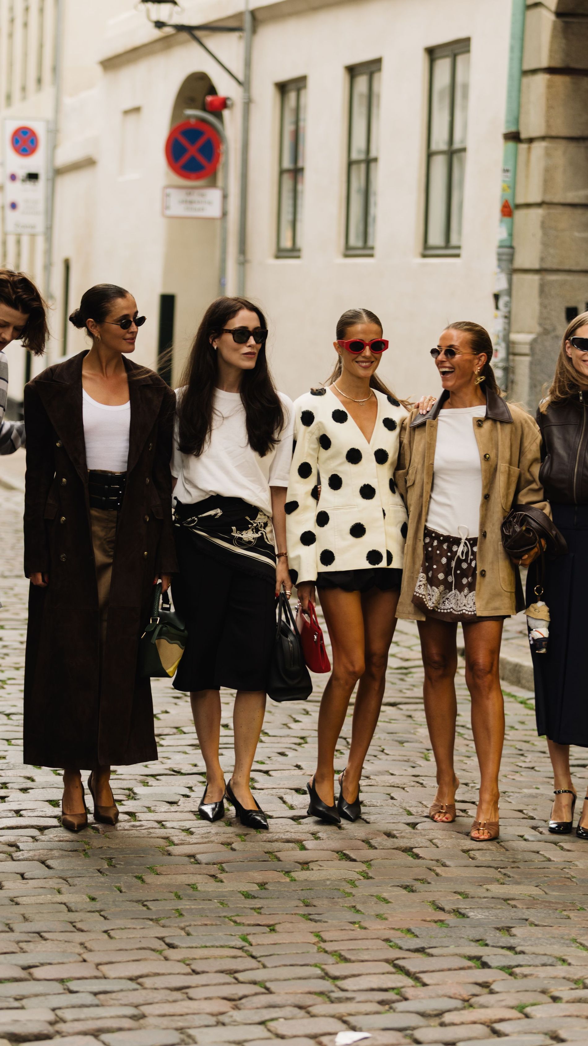 six girls standing on the street smiling during Copenhagen Fashion Week wearing different colorful and standout outfits 
