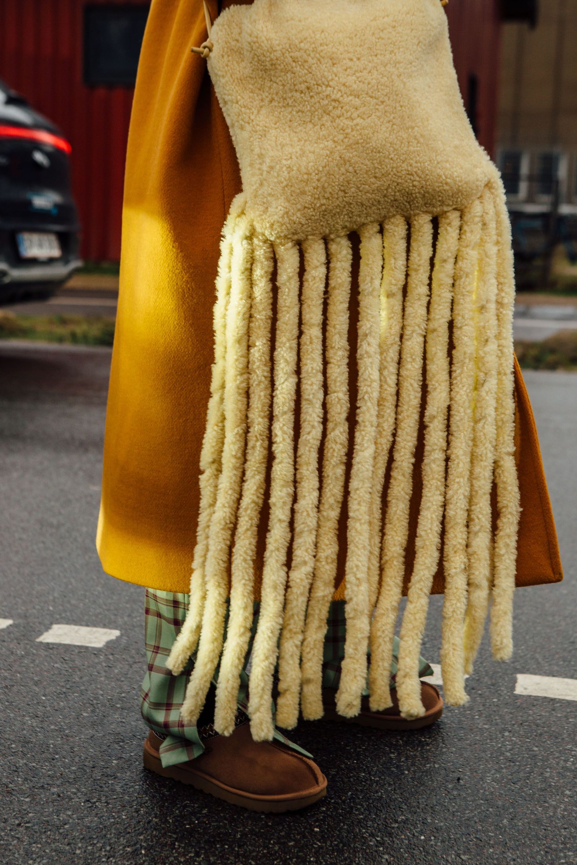 Guest wears a butter yellow faux fur bag with fringe