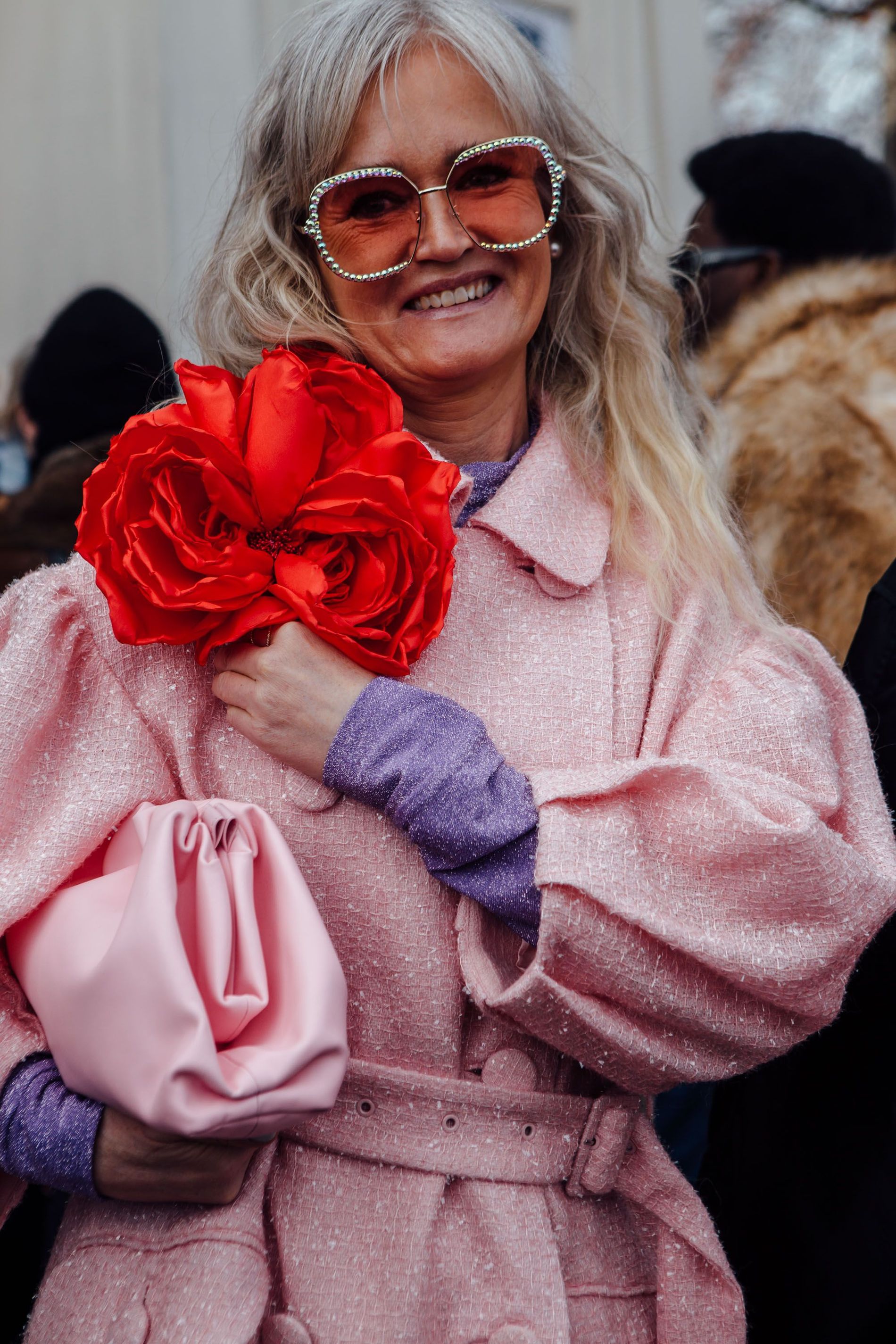 Guest wears a big red flower brooch and pink coat to Copenhagen Fashion Week AW23