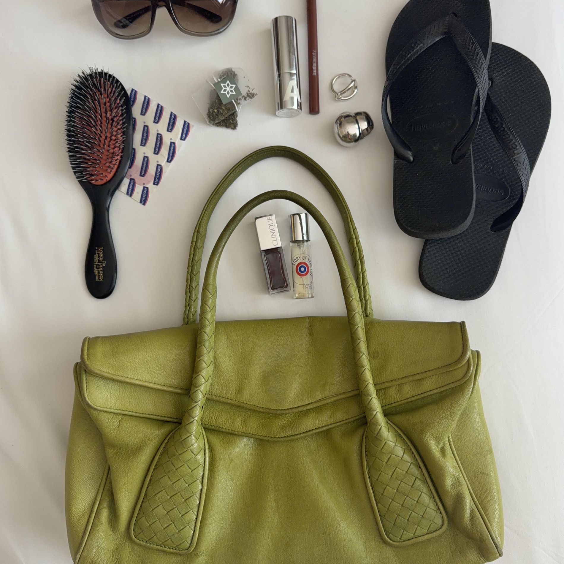 Johanna Lager's green leather bag during CPHFW 2026, filled with Havaianas, makeup, hairbrush, rings, sunglasses and bandages.