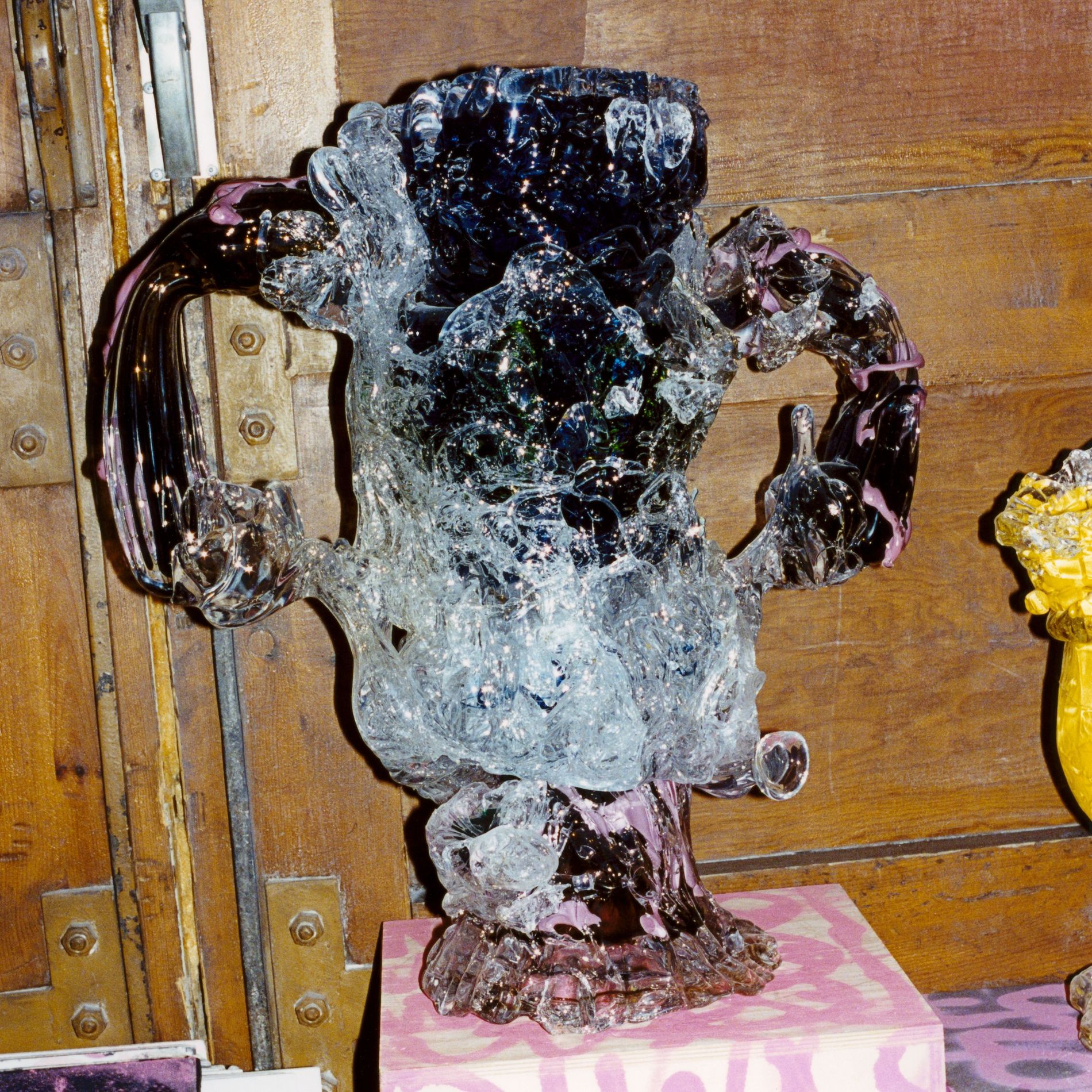 Highley detailed glass sculptured standing on a grafitti podiumwith a wooden background 