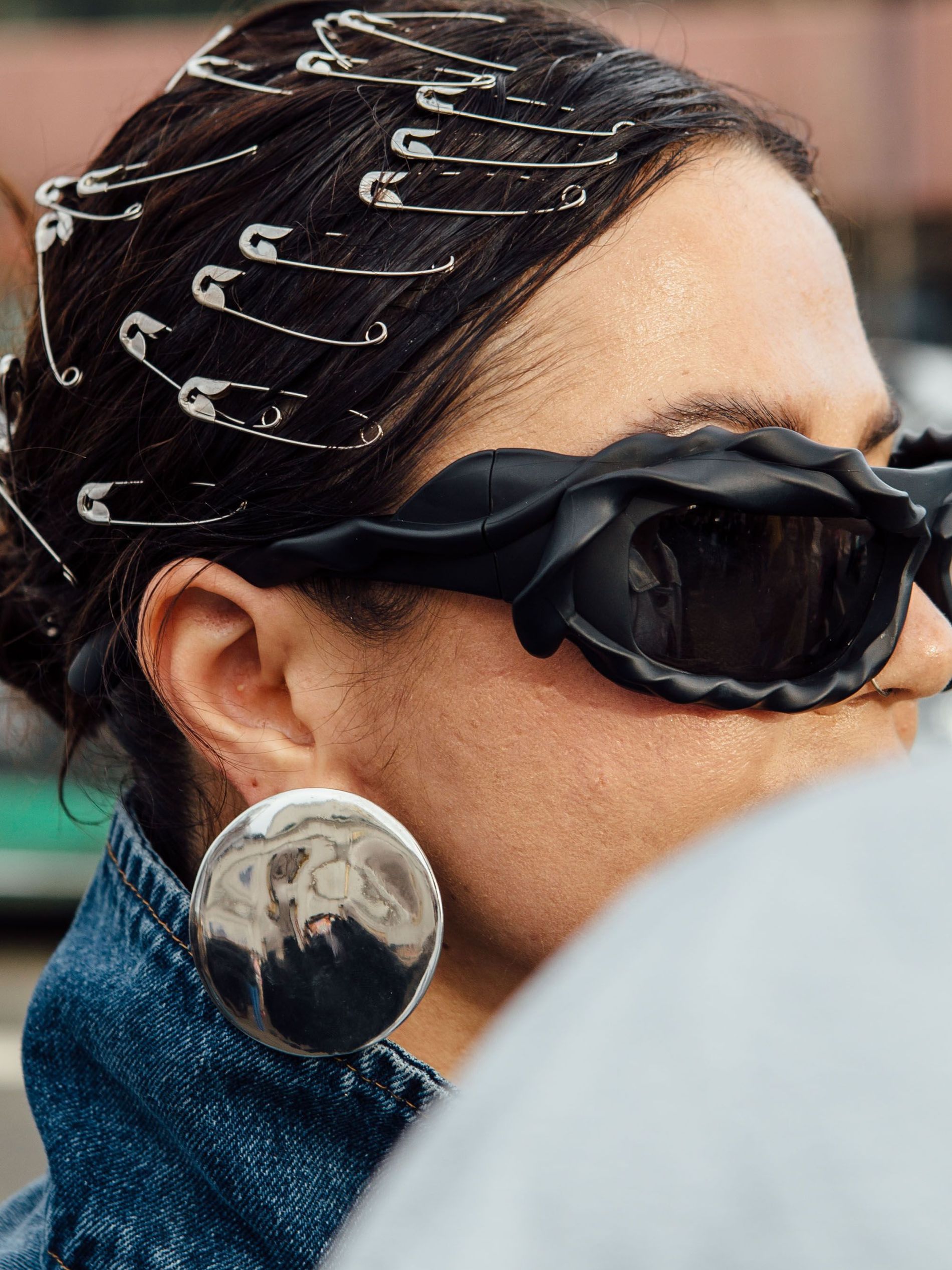 Copenhagen Fashion Week guest wears safety pins attached to a slicked back bun