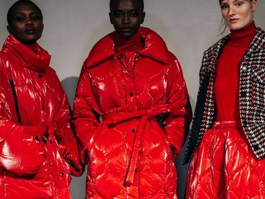 Three models wearing red puffers backstage during Baum Und Pferdgarten's autumn/winter 2022 show