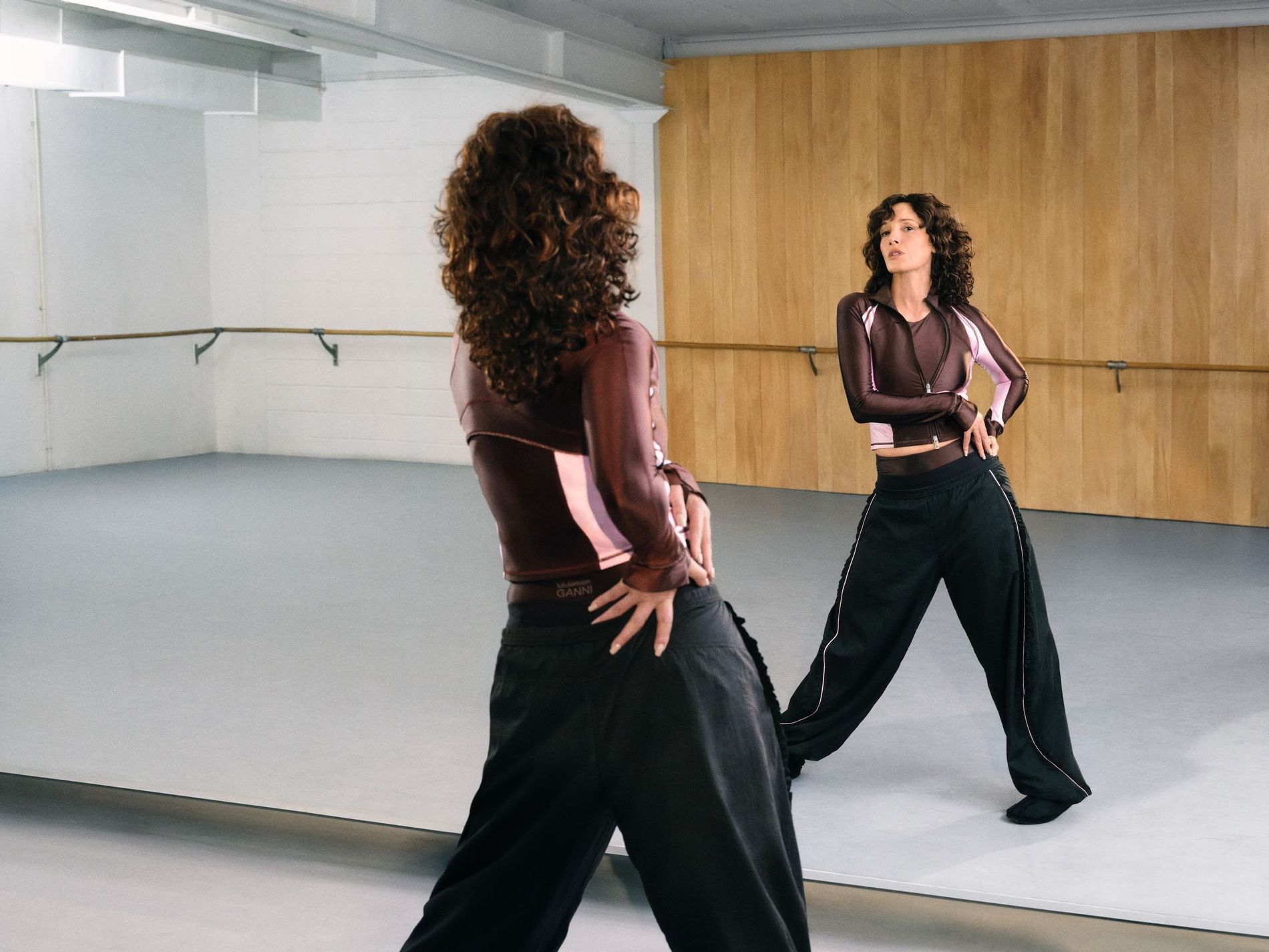 Actor Jennifer Beals wearing the Ganni x Lululemon poses near a mirror.