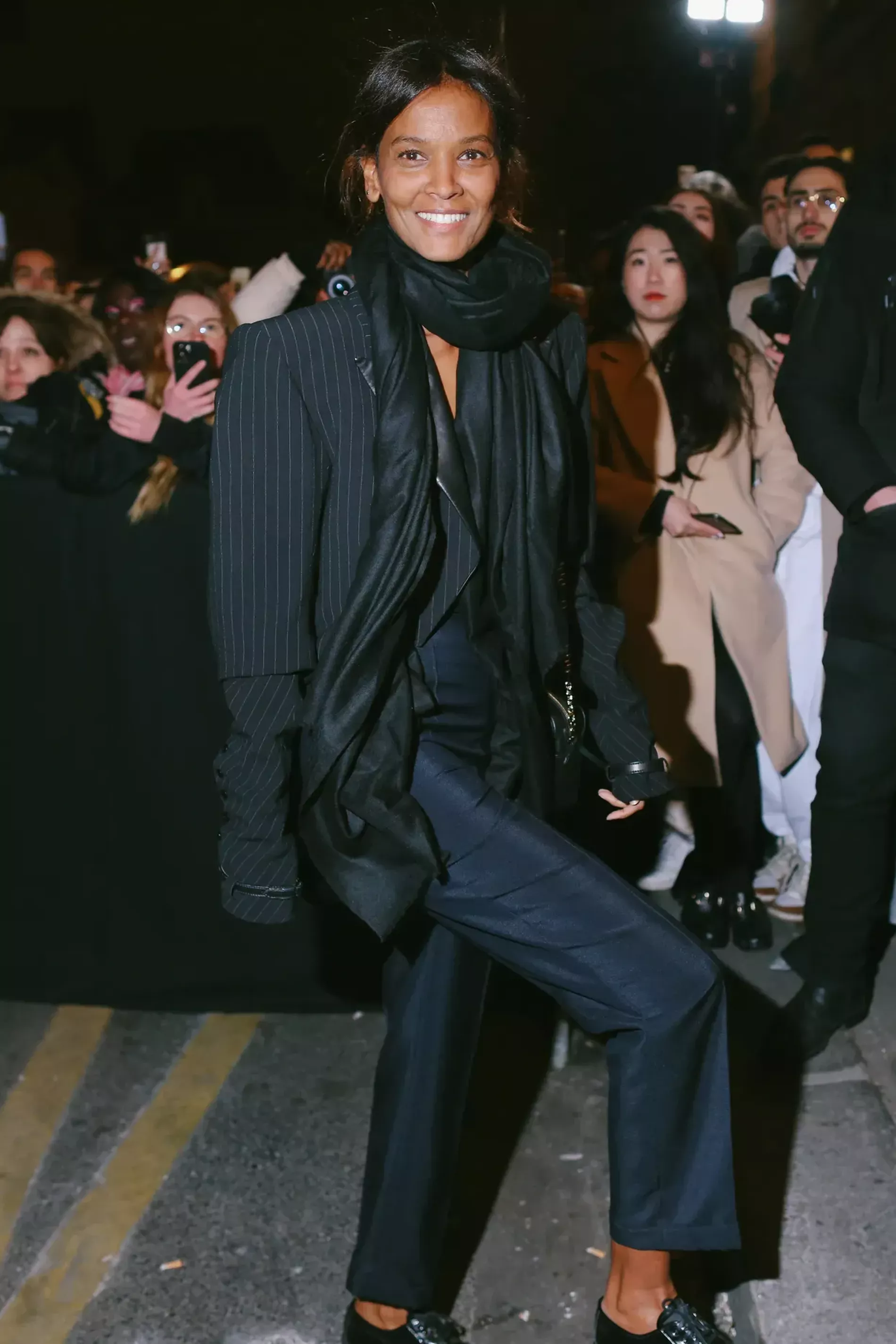 Paris Fashion Week guest wears pinstripe blazer with dark blue suit pants and black scarf 