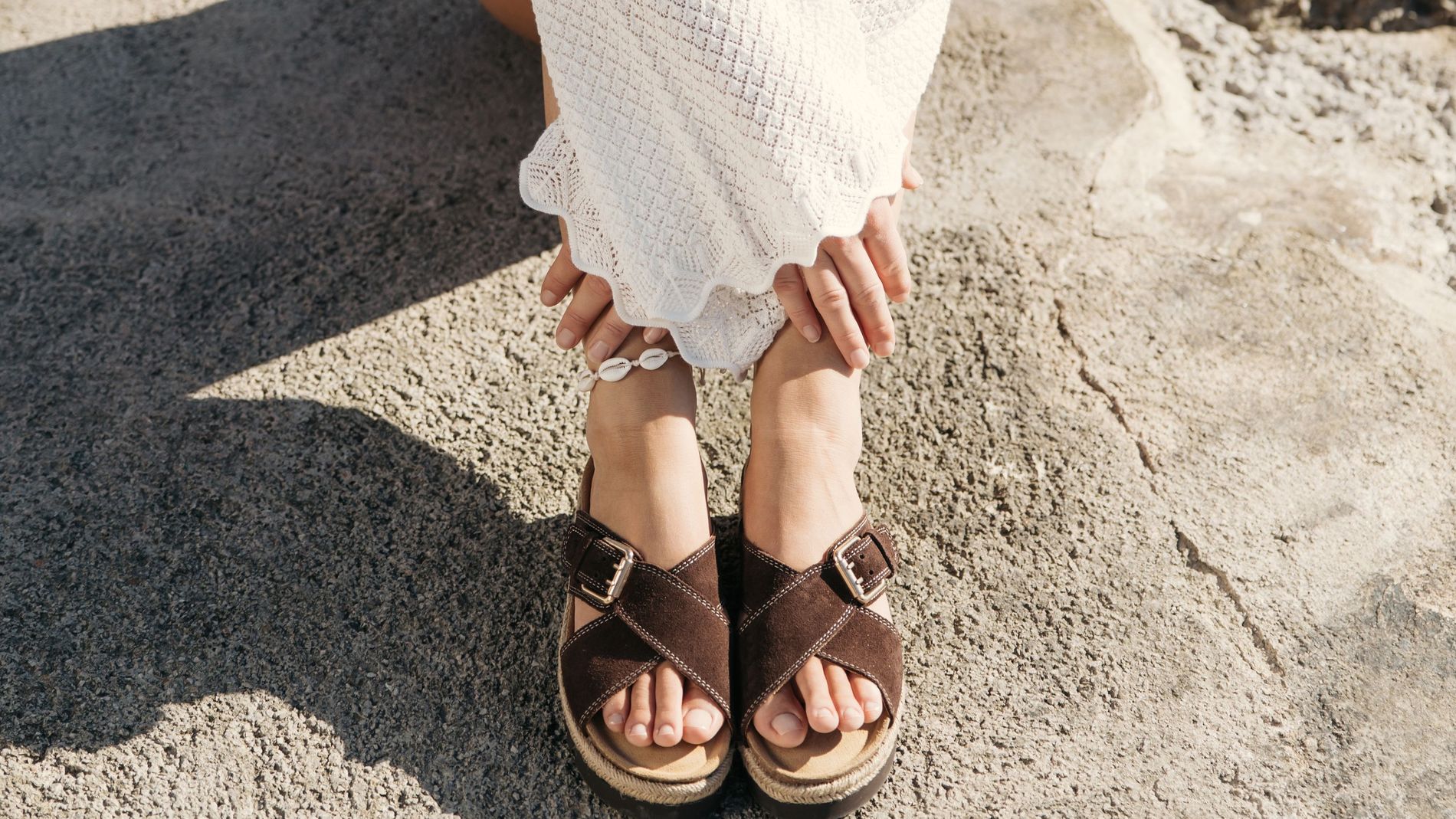 Model wears criss-cross sandals on a cliff