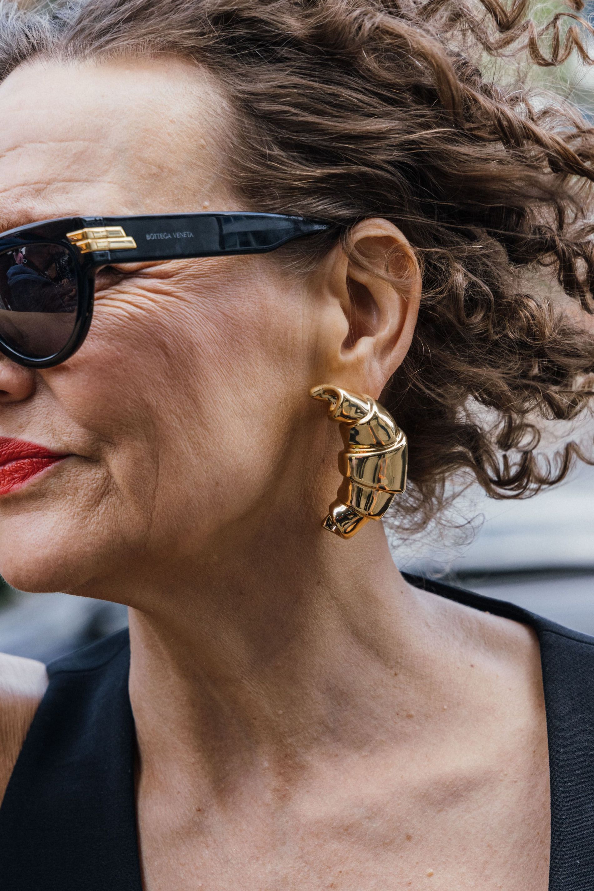 Guest wears a pair of gold croissant statement earrings to Copenhagen Fashion Week SS24