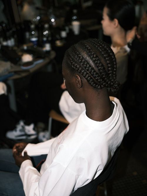 Model wears braids in a bun backstage at Saks Potts AW23 show