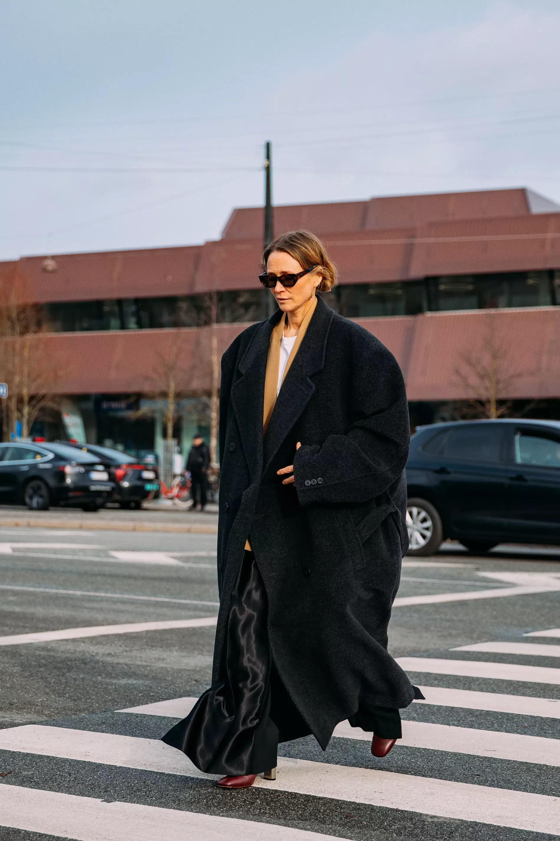 Copenhagen fashion week guest wears oversized dark grey coat and black silk pants 