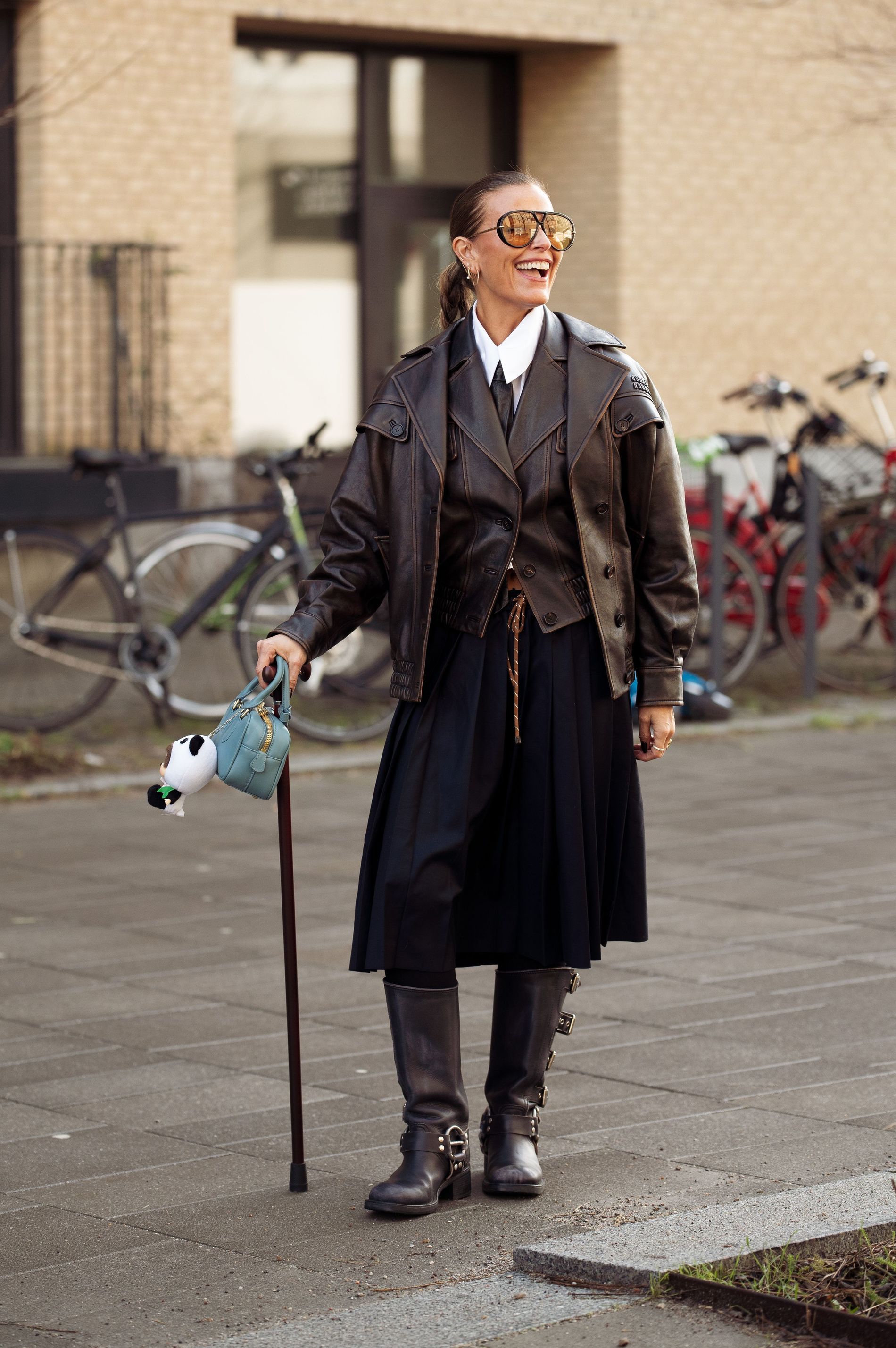 Janka Polliani captured on the street wearing brown leather jacket, white shirt and black tie. 