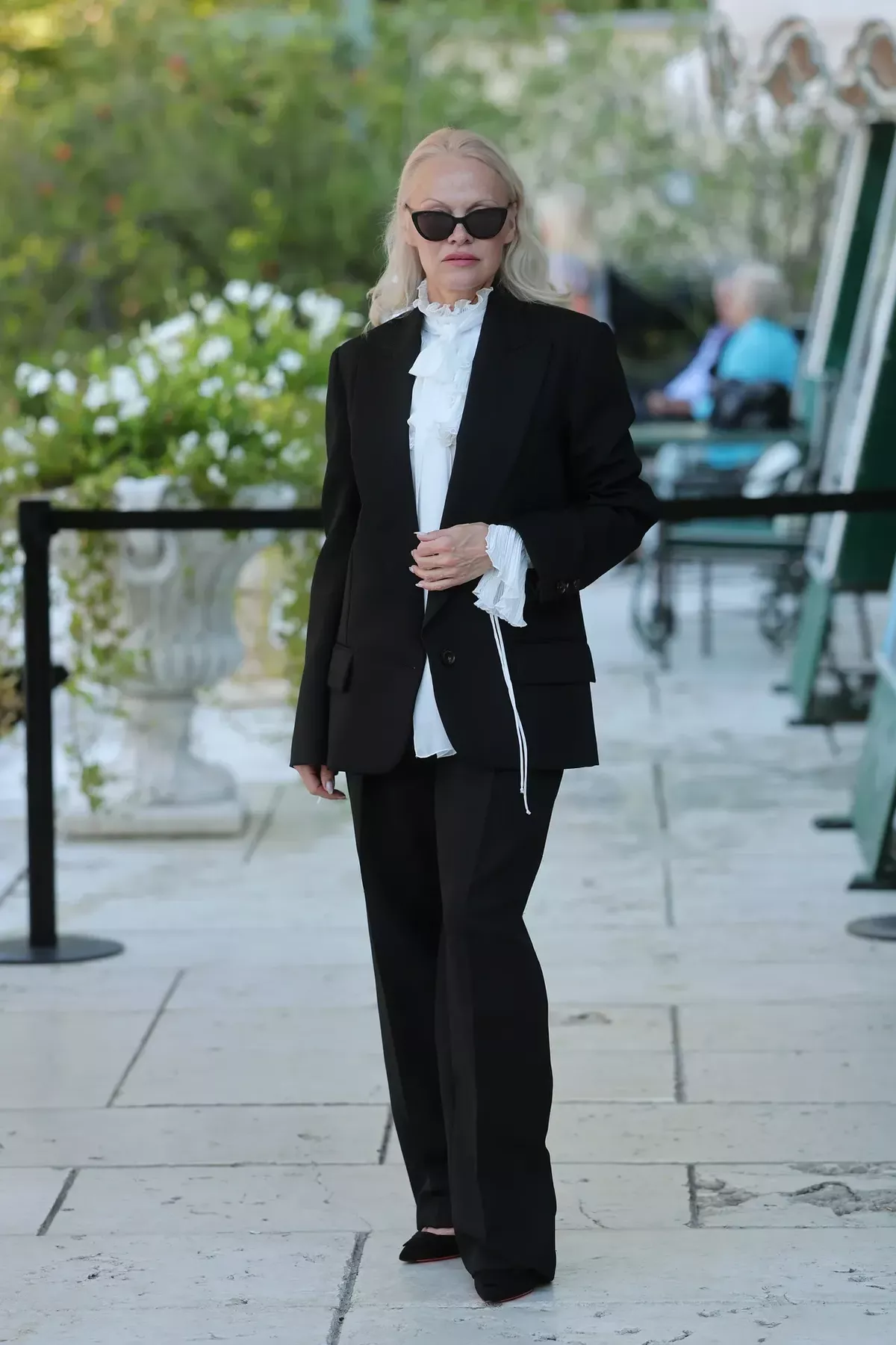Pamela Anderson photographed wearing a suit and frilled shirt at the Venice Film Festival
