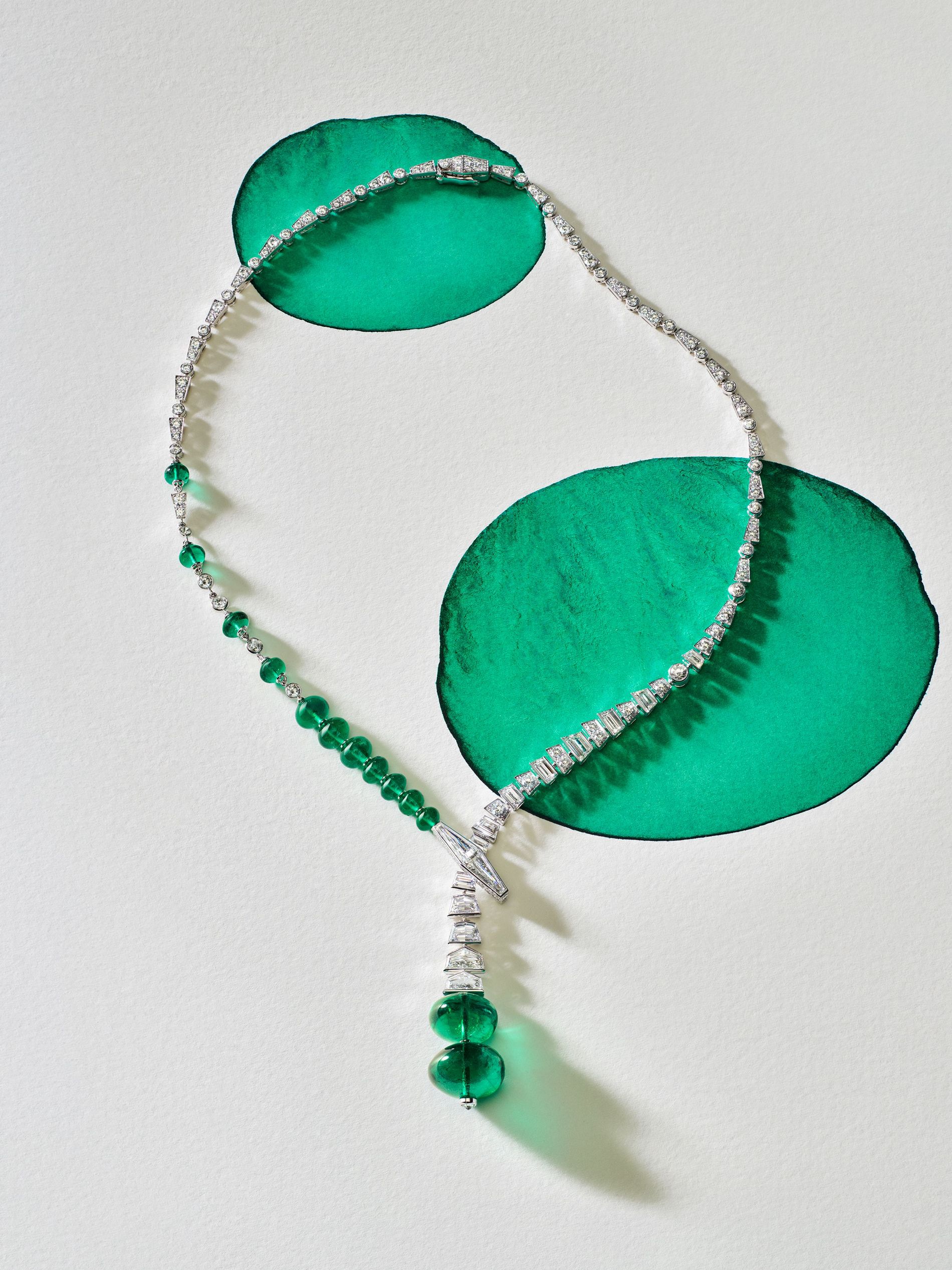 An emerald and diamond necklace from Cartier high jewellery against a white background atop two green ovals painted