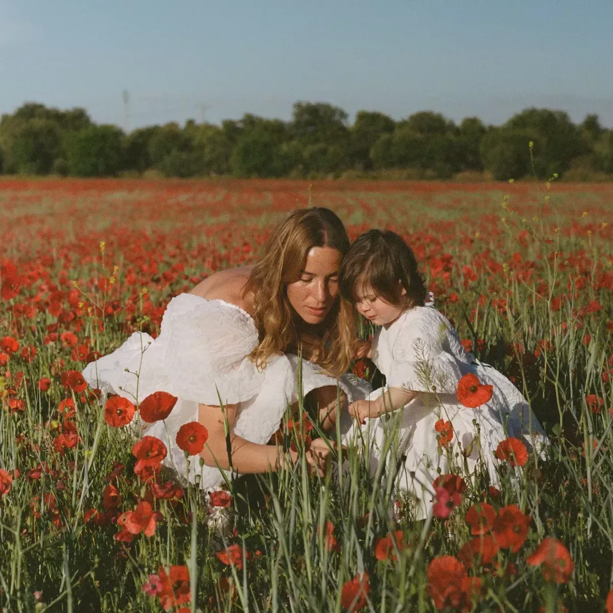 A mother and her child pose in a poppy field
