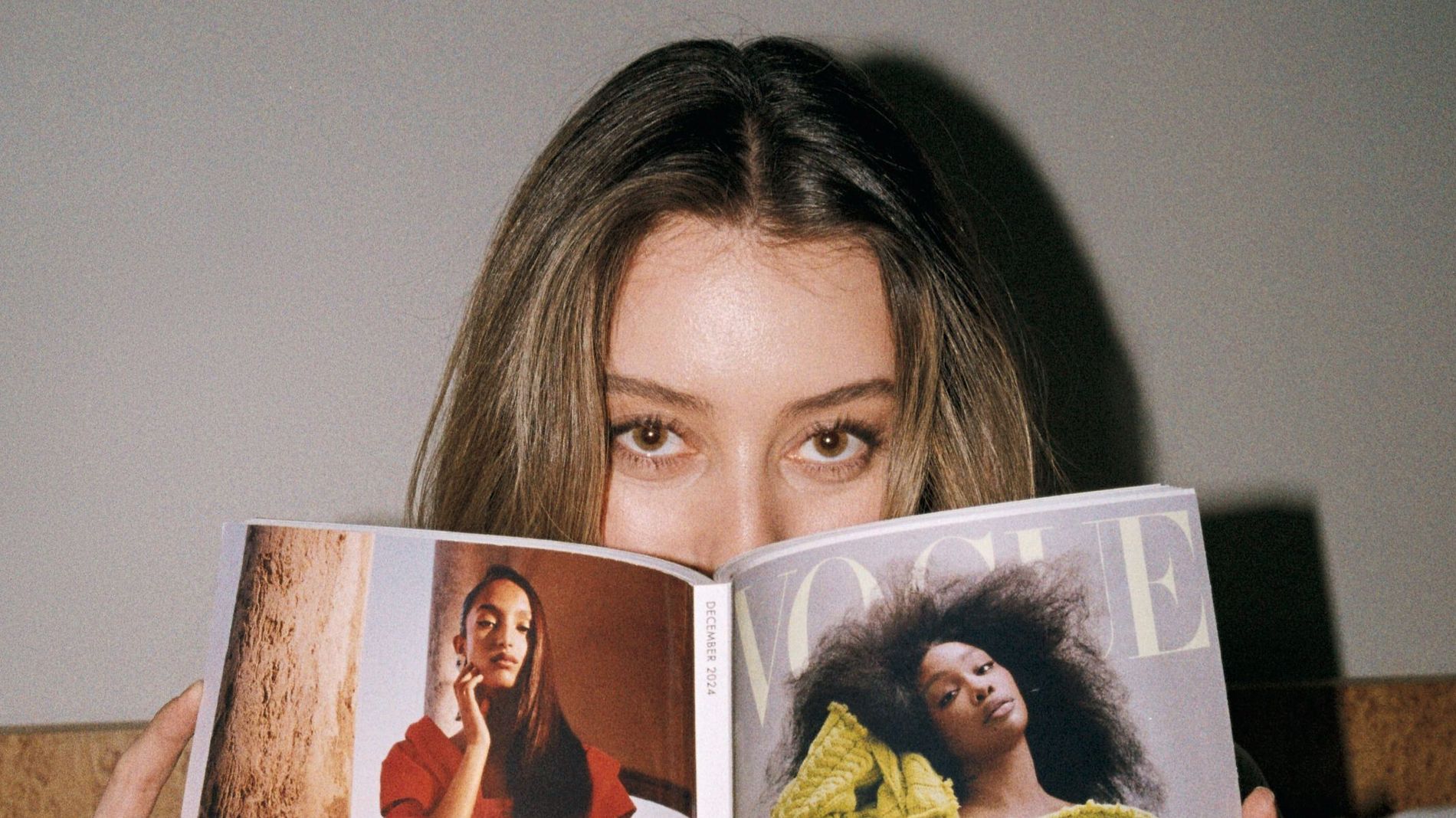 A model with brushed up brows is pictured reading a Vogue magazine