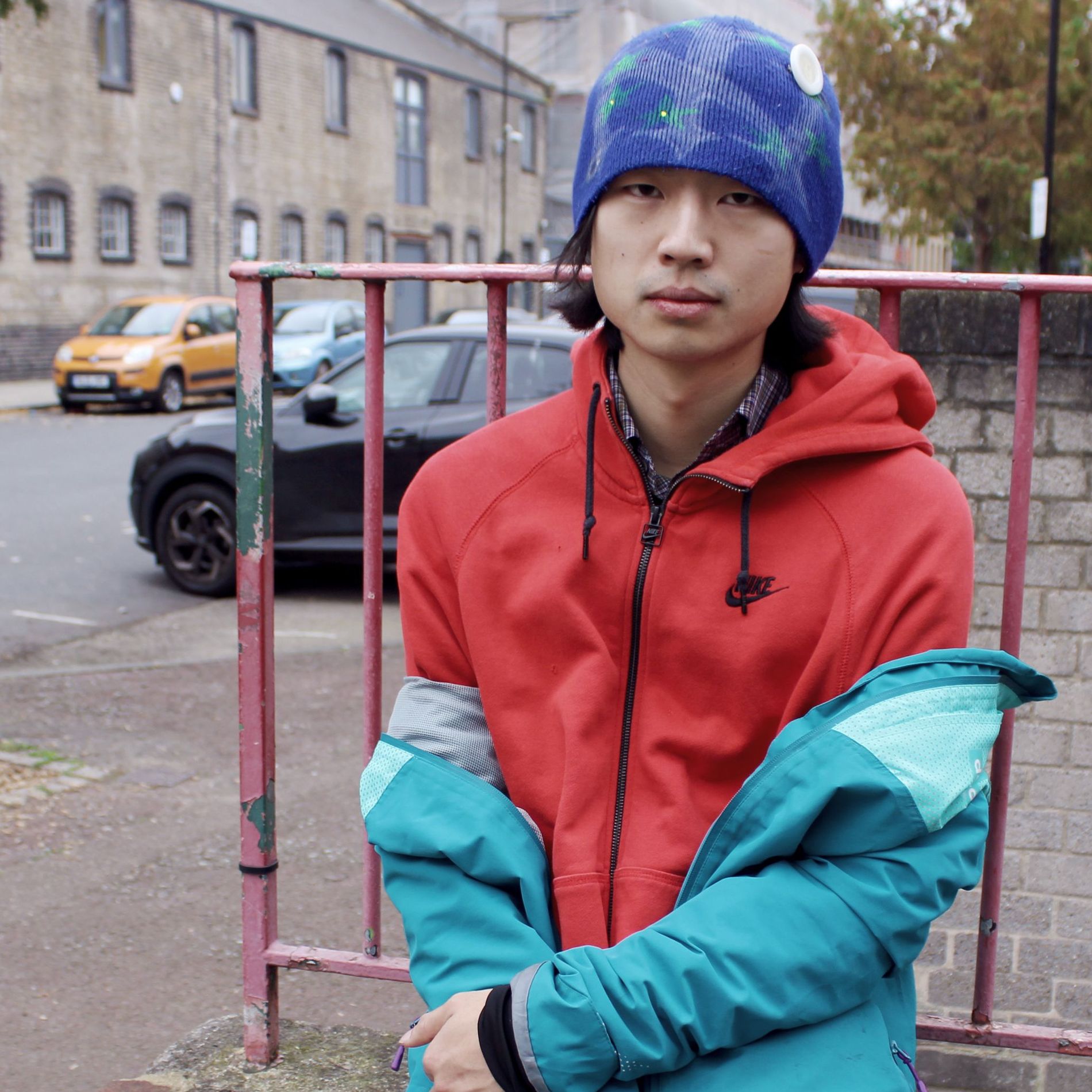 A man leaning on a fence on a street