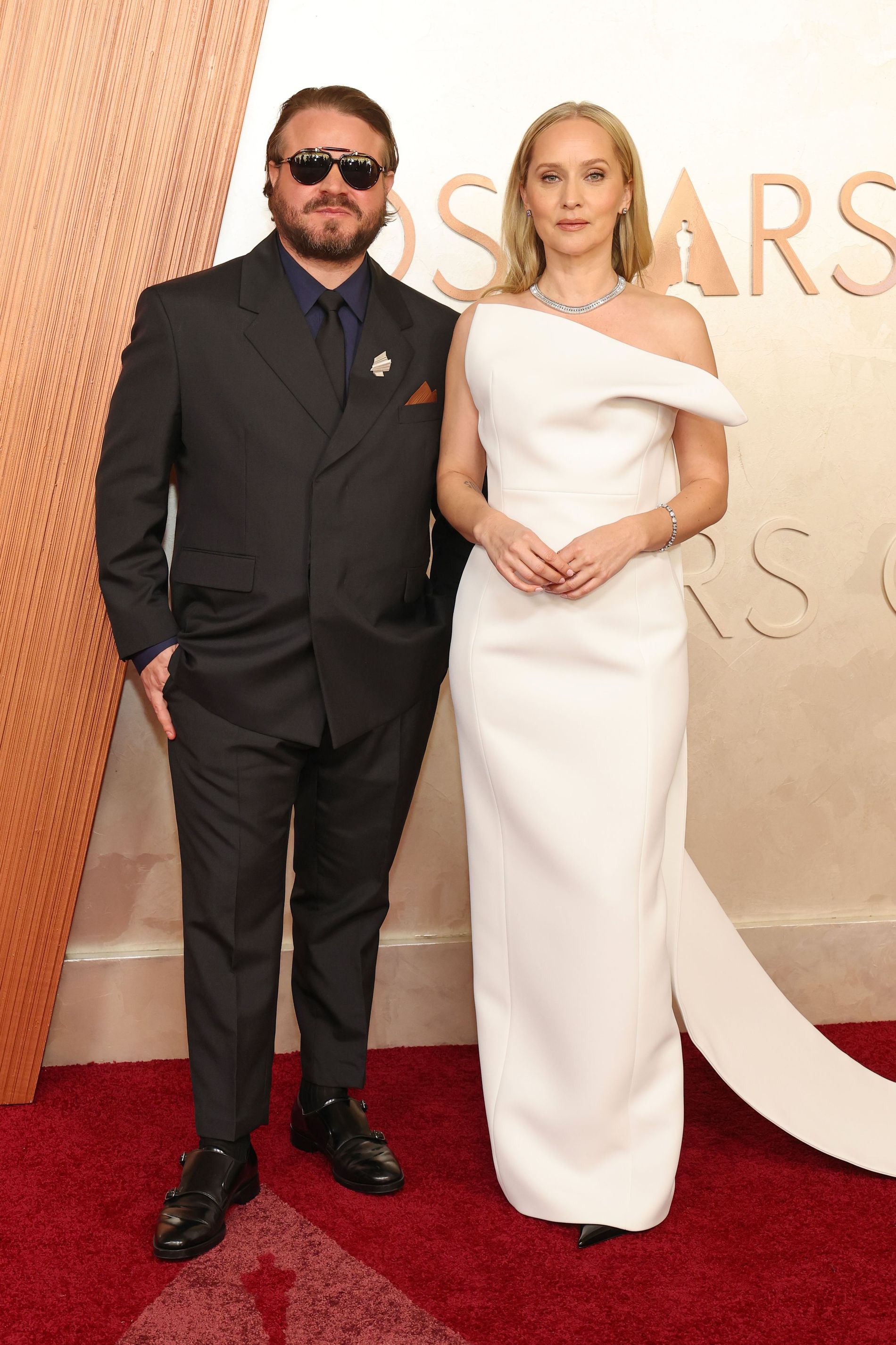 Brady Corbet and Mona Fastvold attend the 97th Annual Oscars. Mona is wearing a white dress by Khaite 