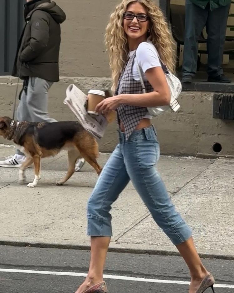 Emili Sindlev looks the spitting image of Carrie Bradshaw wearing denim capris, a baby-T layered under a vest and sky-high heels during NYFW street style