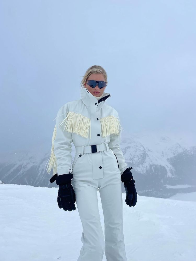 Elsa Hosk poses in a fringed, belted ski suit with mittens and tinted shades in St Moritz