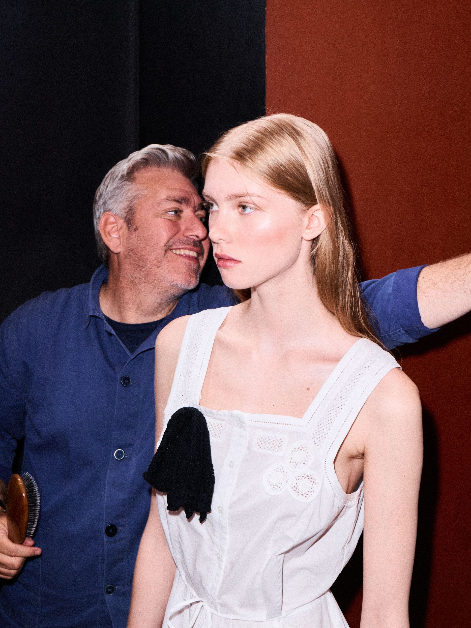 Hair stylist Cim Mahony is adjusting a model's hair before the runway