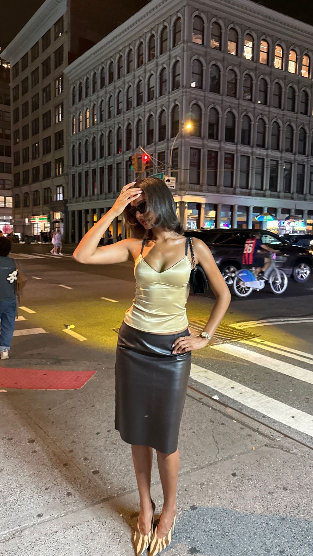 Jamilla Strand wears a yellow satin top, black leather midi skirt and patterned heels