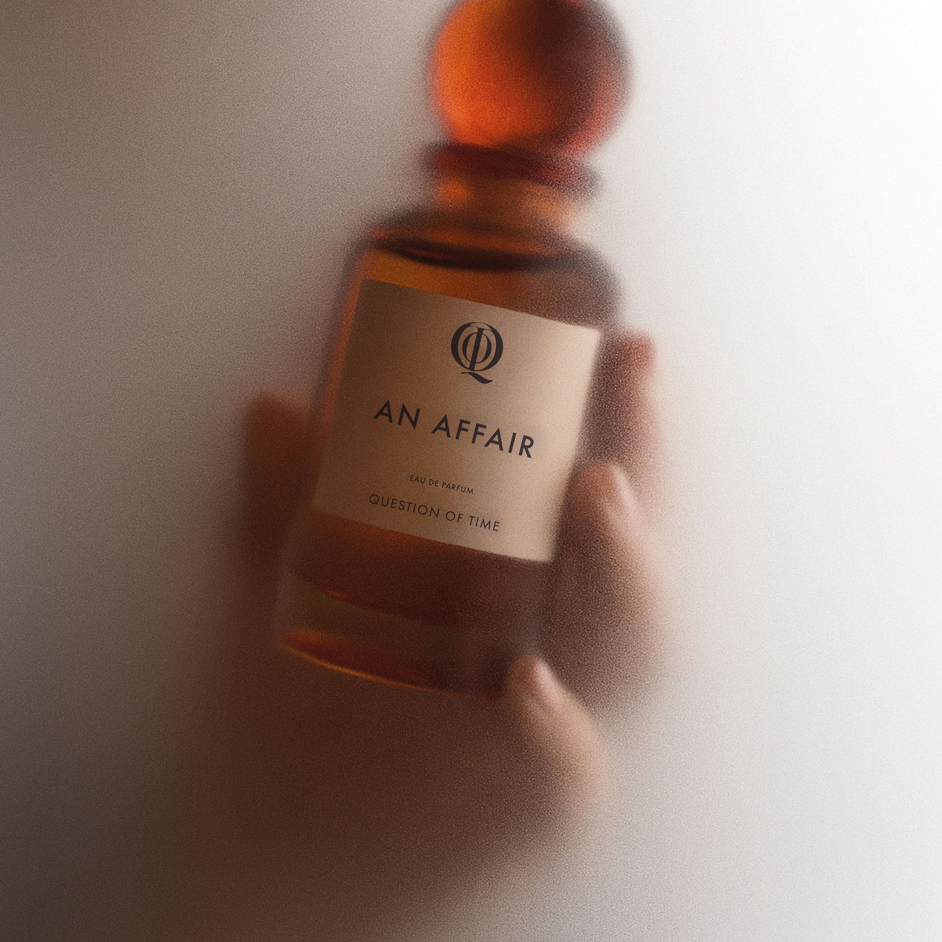 QOT's perfume 'An Affair' held in hand and surrounded by steam