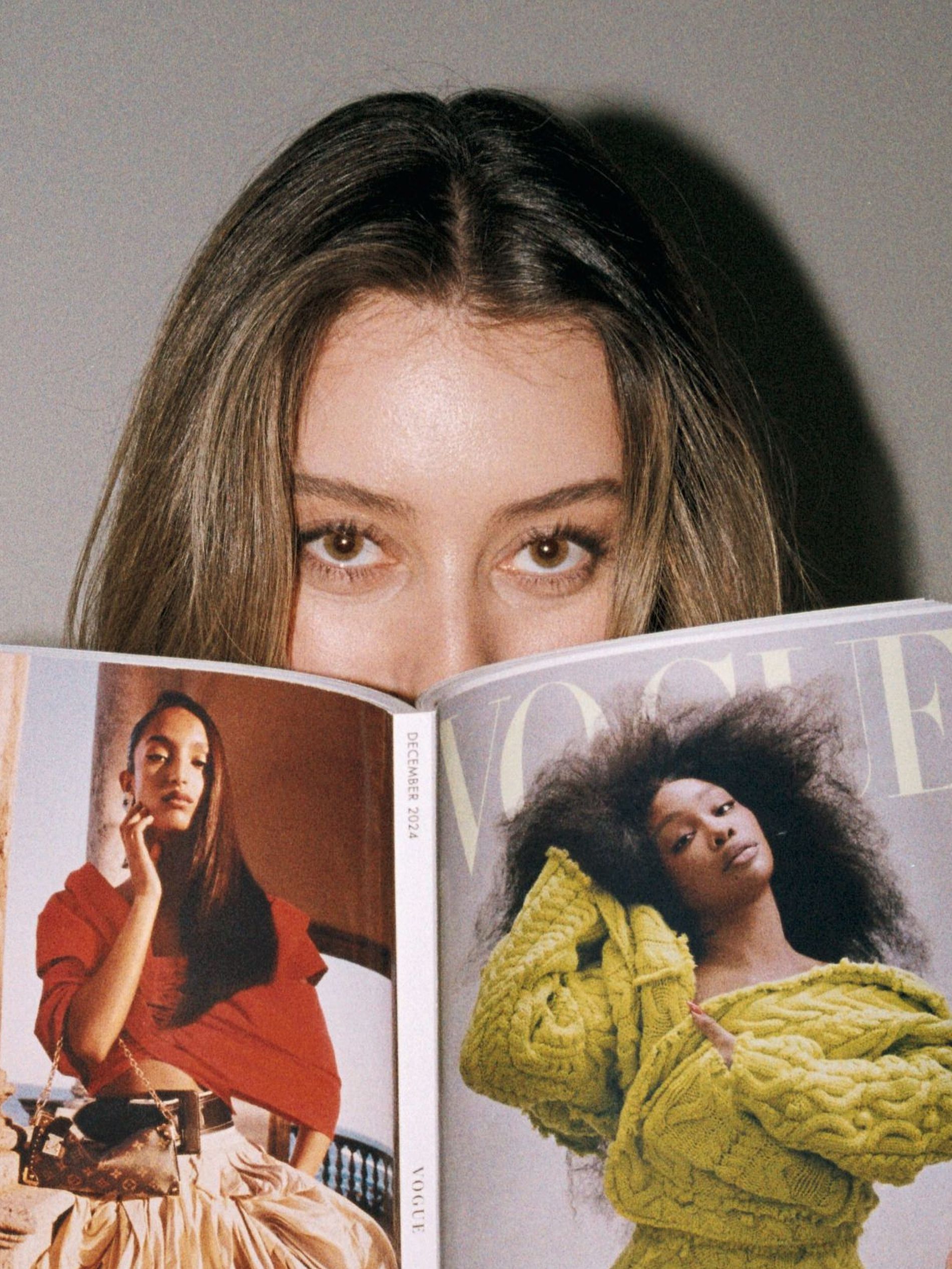 A model with brushed up brows is pictured reading a Vogue magazine