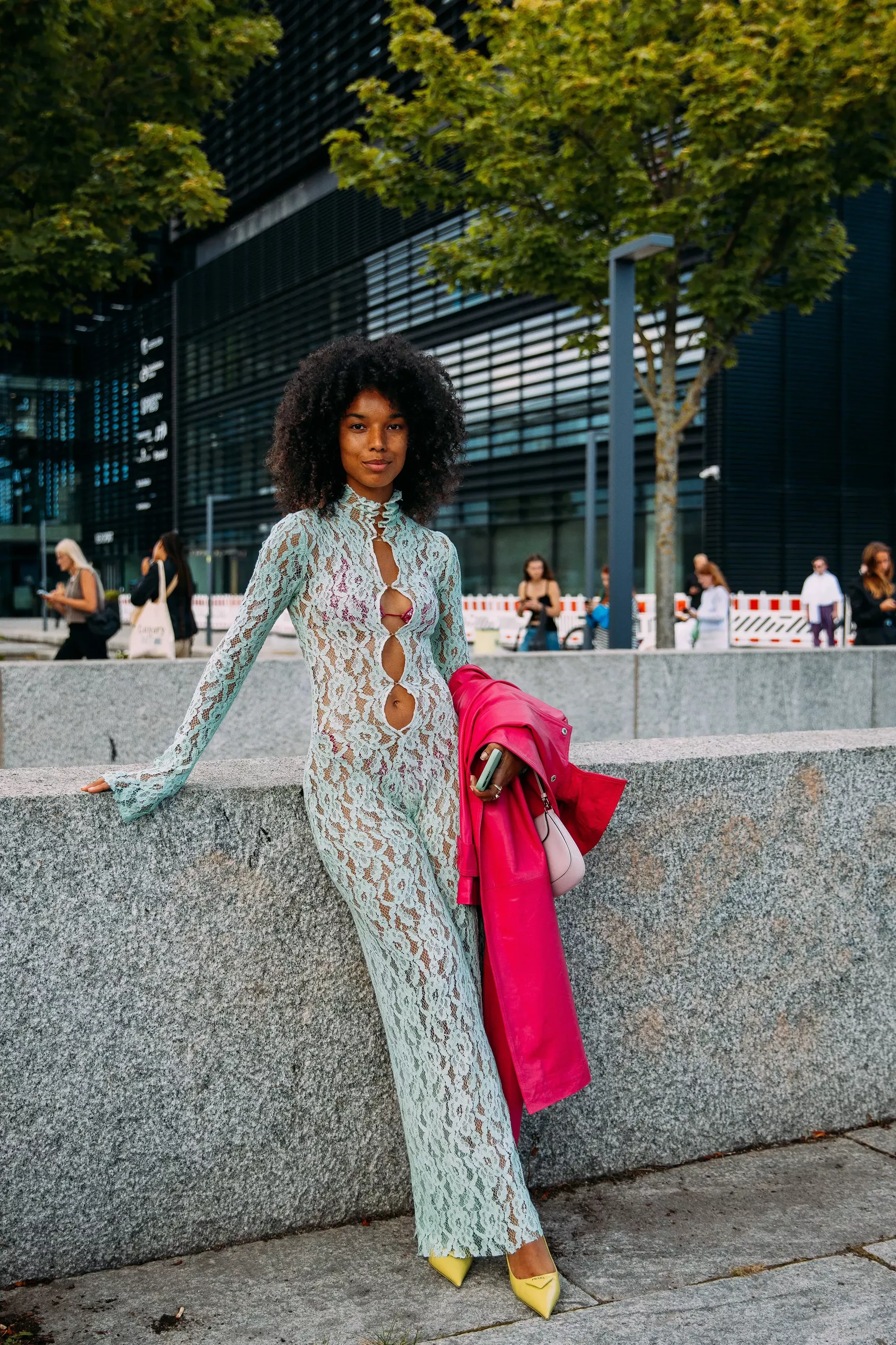 Copenhagen fashion week guest wears lace dress with bright pink coat