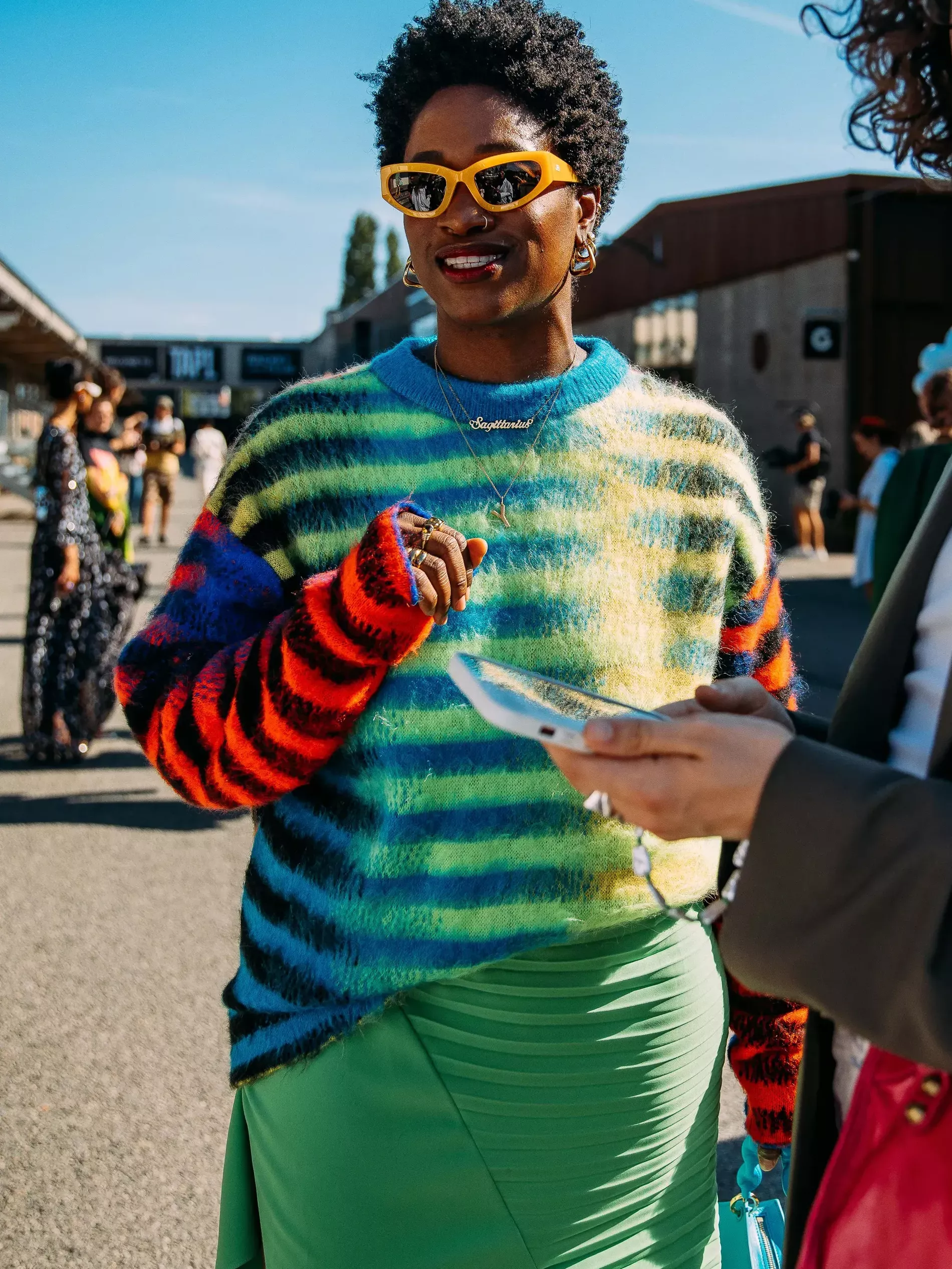 Copenhagen fashion week guest wears colourful striped sweater over light green skirt 