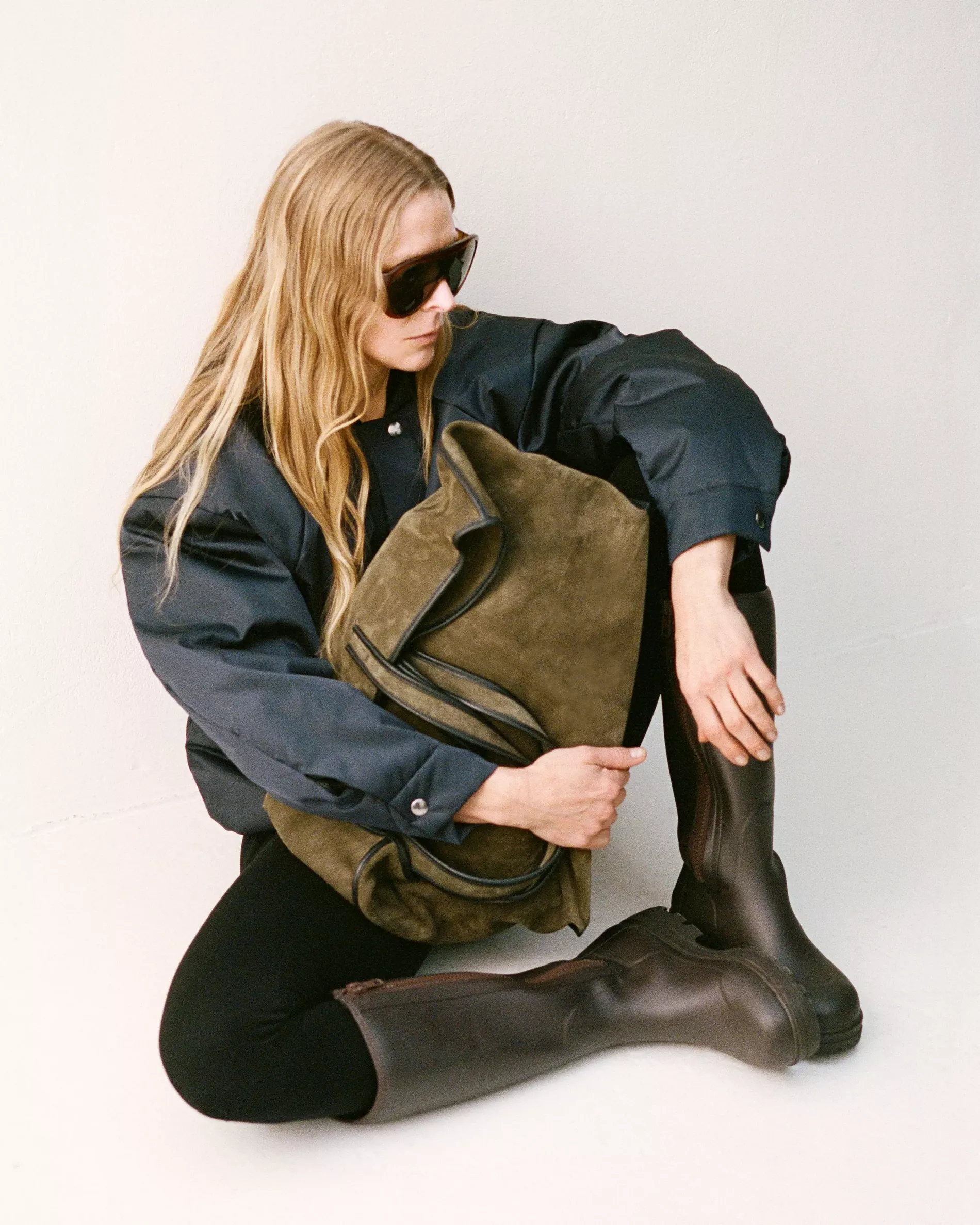 A model sitting on the floor in stylish clothes and rubber boots