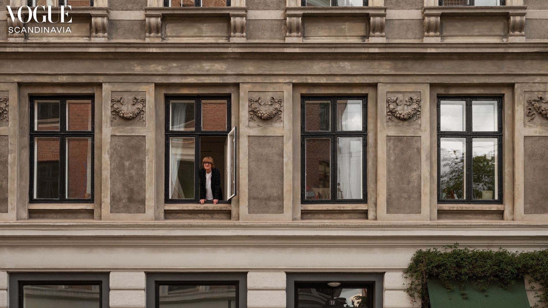 Outside of a apartment building, Gun Gordillo standing looking out of one of the windows