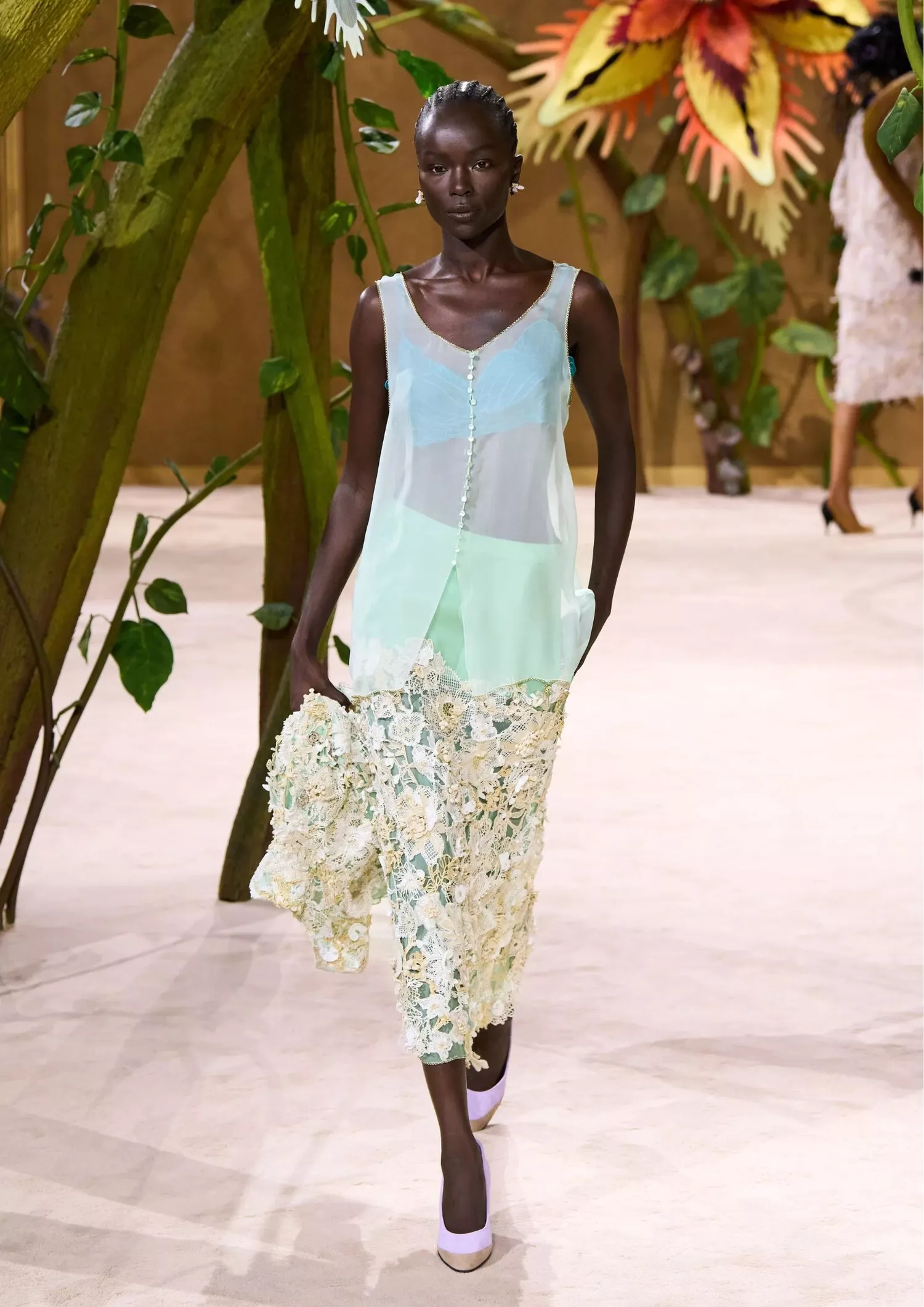 Sheer sleeveless top with a floral lace appliqué skirt, paired with pointed-toe pumps