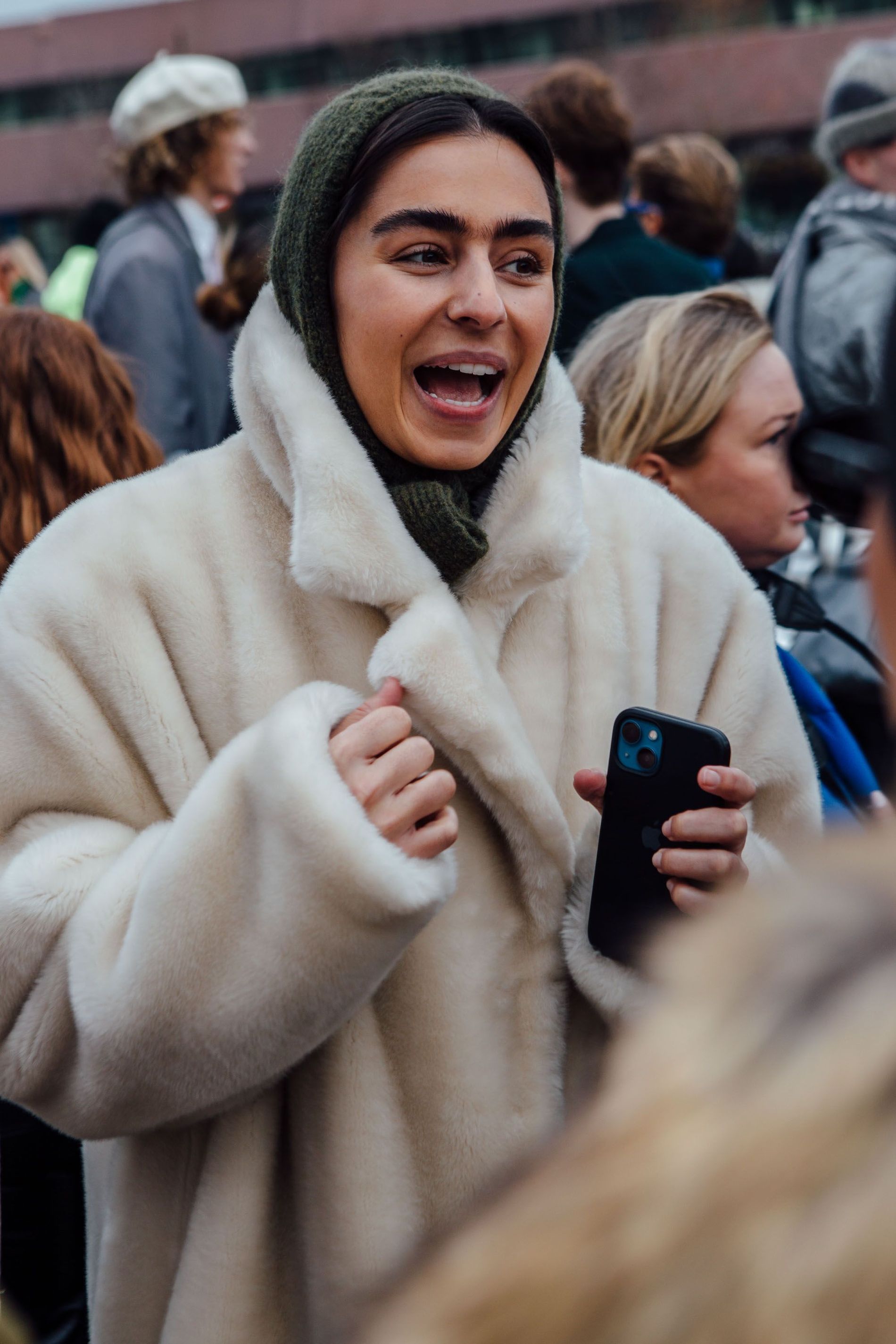 A guest wears an army green balaclava with a white faux fur coat