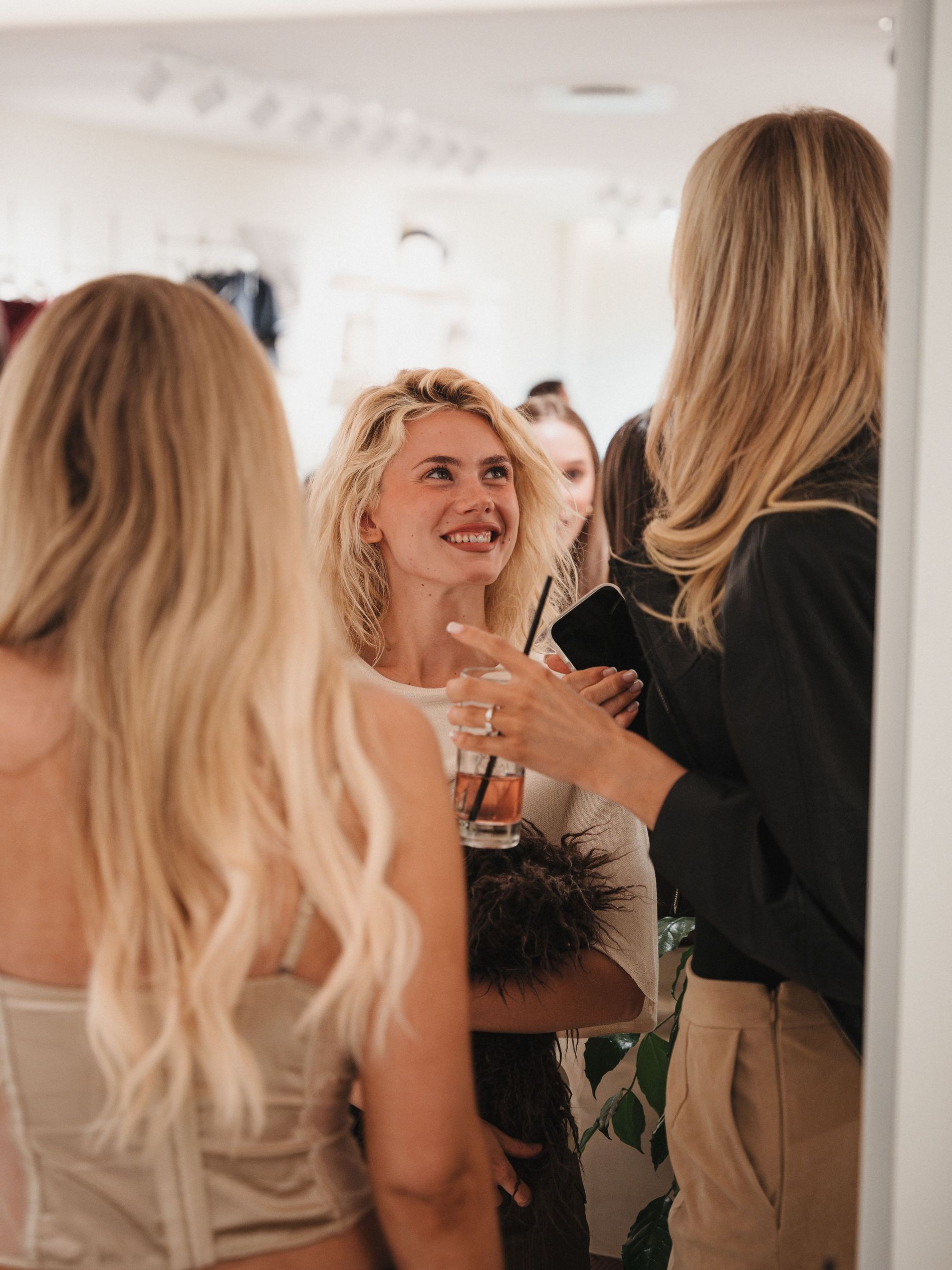 Three girls socializing with drinks and nibbles at the Intimissimi X Vogue Scandinavia event
