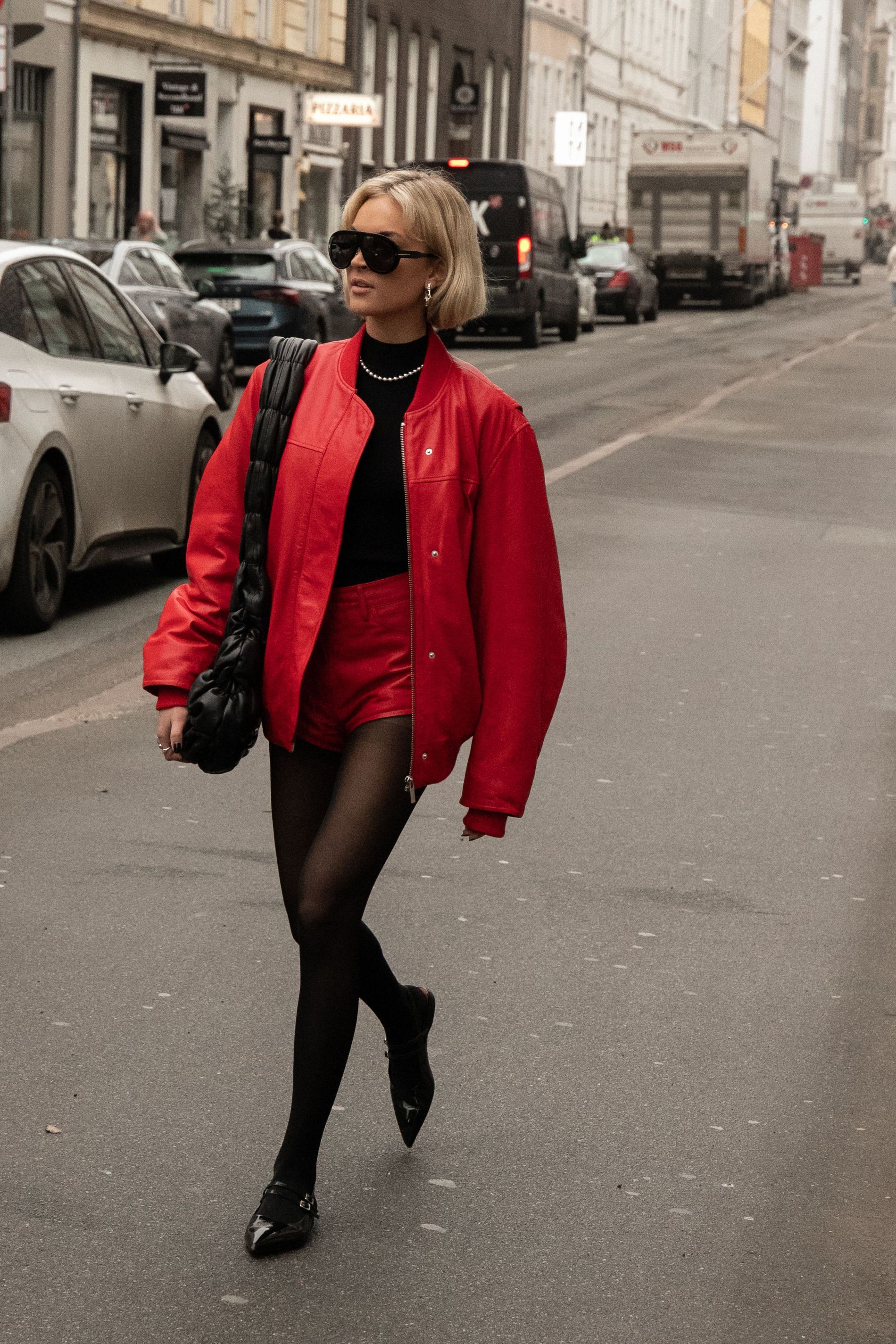 A guest wears a matching red leather bomber and red mini shorts with black stockings and ballet flats