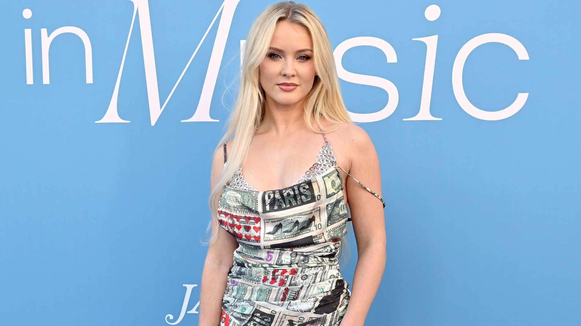 Zara larsson attending the Billboard music awards wearing a patterned dress with white suede boots and black feather dress 