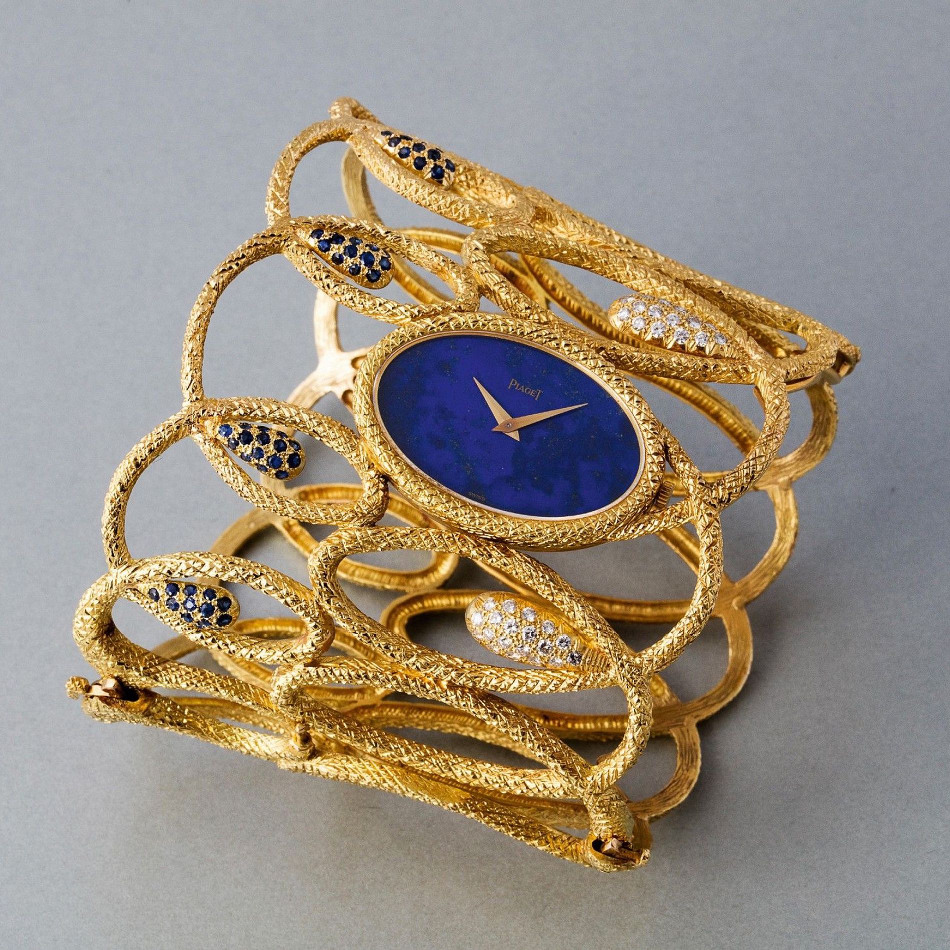 Piaget  Ref. 9550D571  A highly exclusive and sumptuous yellow gold bangle watch with lapis lazuli dial and set with sapphires and diamonds  1971  61mm. Width 210mm. Max length  Case, dial and movement signed  Estimate CHF30,000 - 50,000 