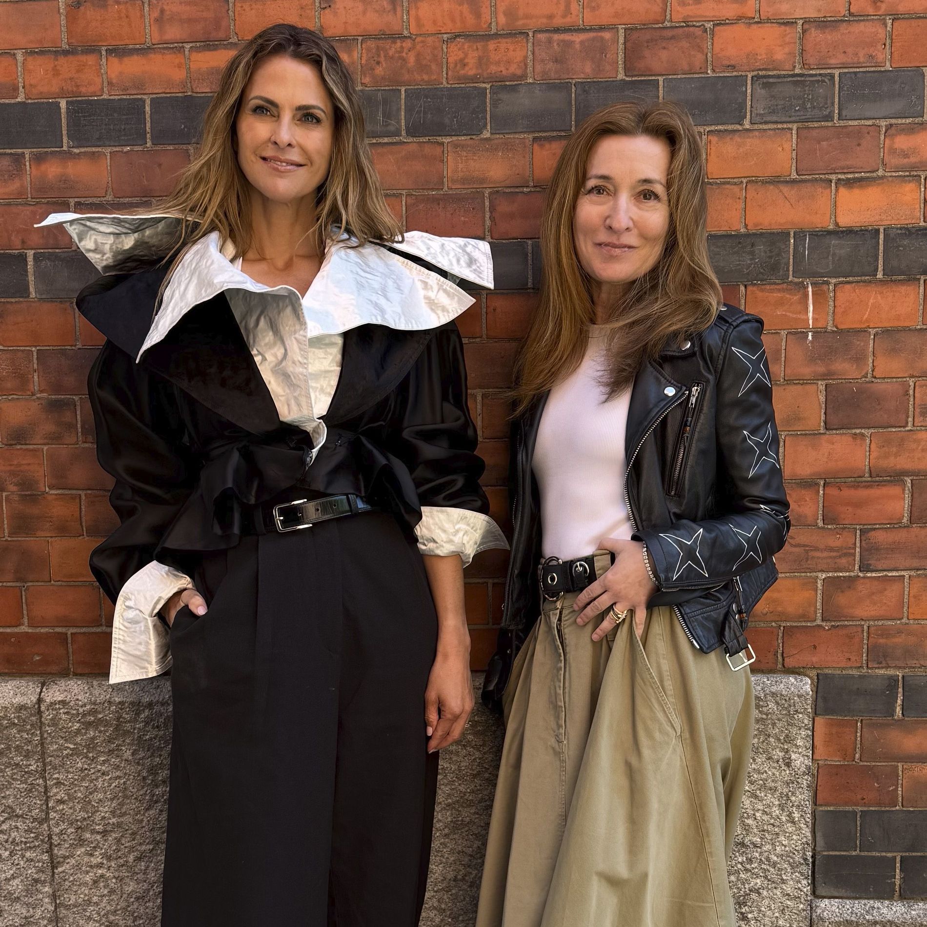 Princess Madeleine and Martina Bonnier stand side by side by a brick wall