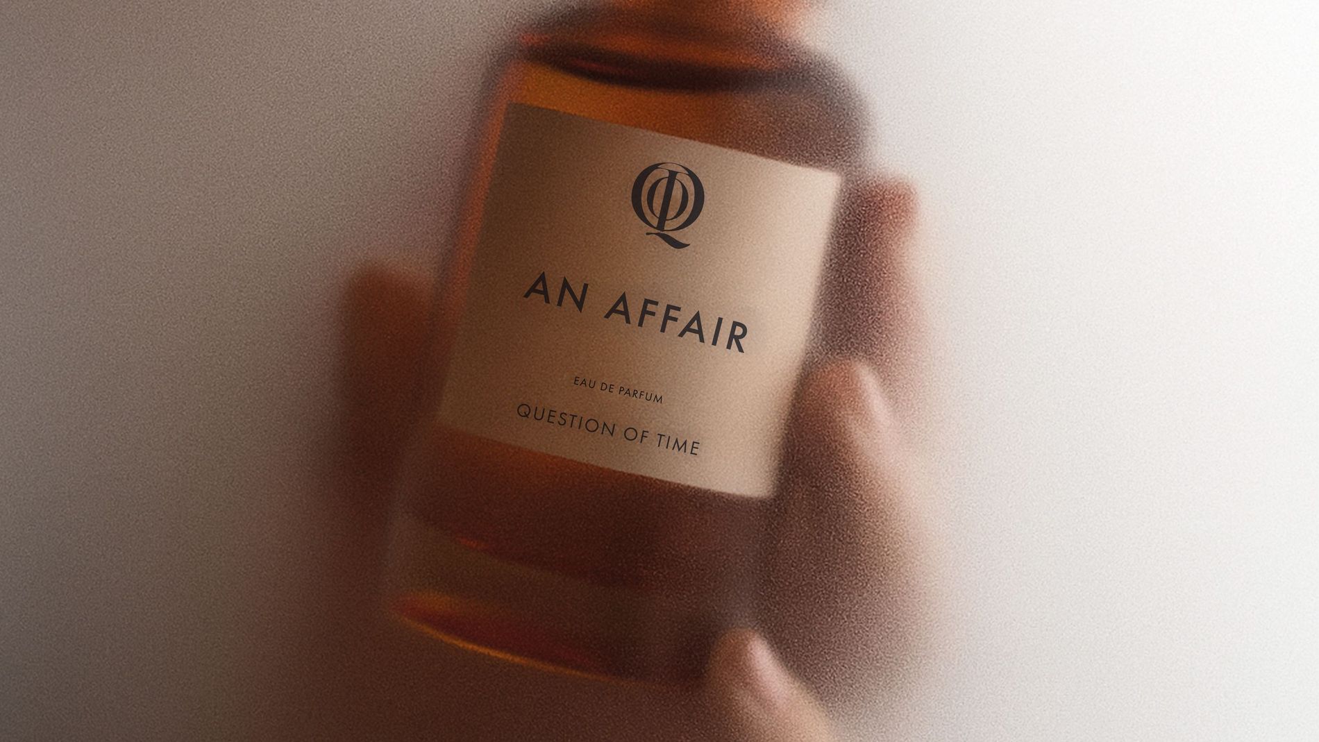 QOT's perfume 'An Affair' held in hand and surrounded by steam