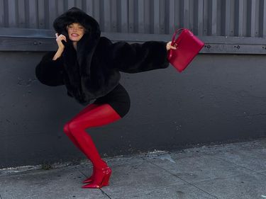 Elsa Hosk wears a faux fur jacket, a black mini dress and red stockings