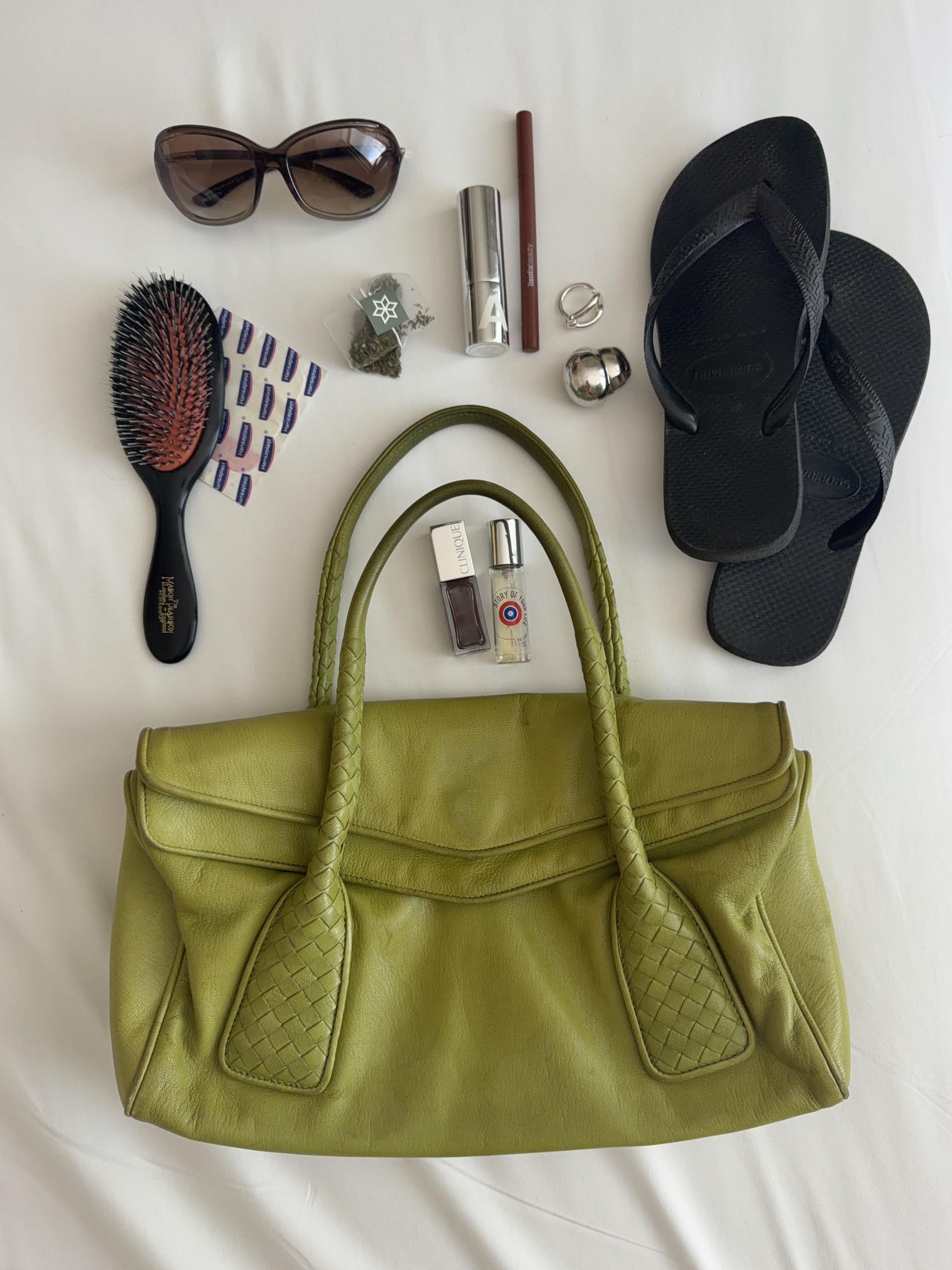 Johanna Lager's green leather bag during CPHFW 2026, filled with Havaianas, makeup, hairbrush, rings, sunglasses and bandages.  