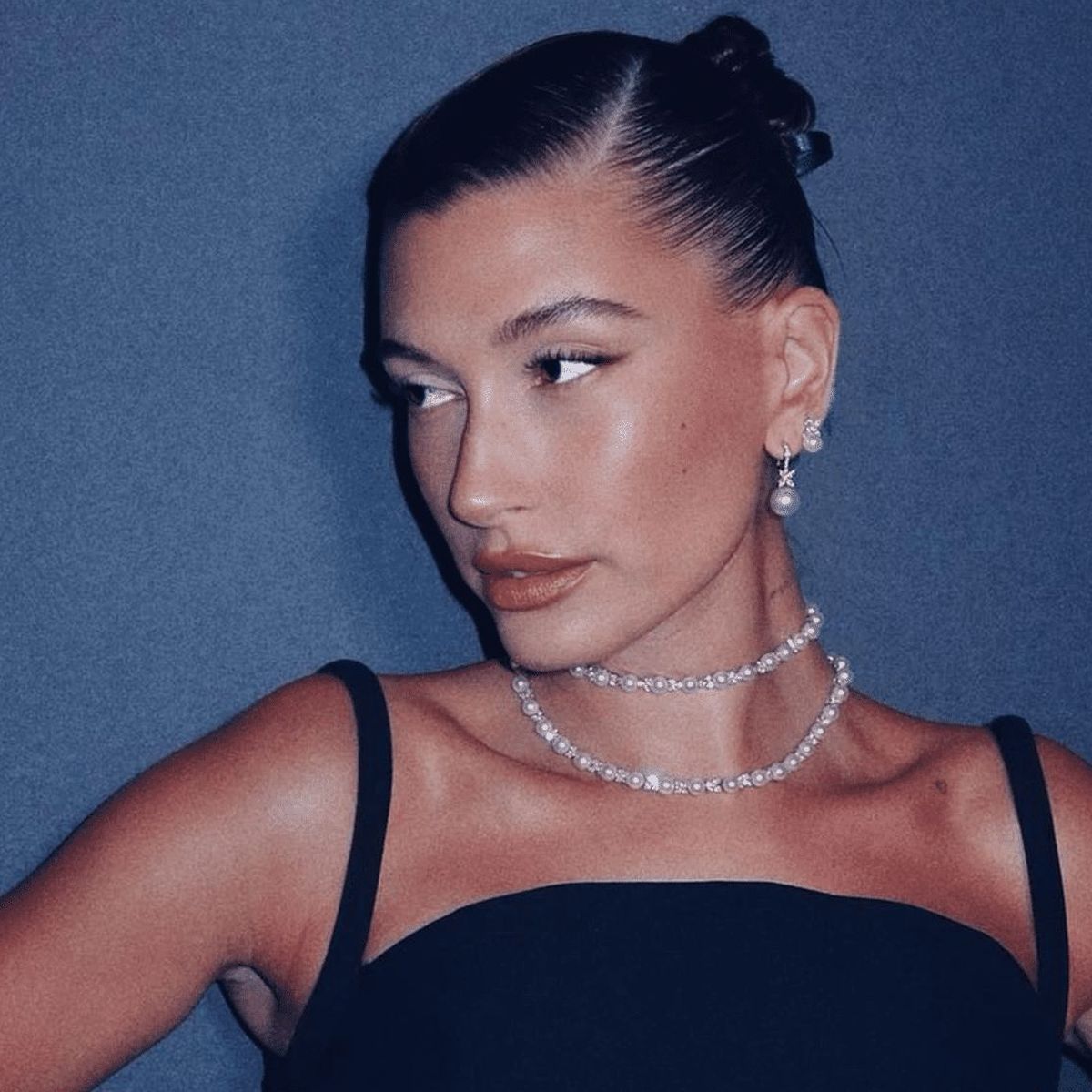 Hailey Bieber in a slicked back bun with a side part.